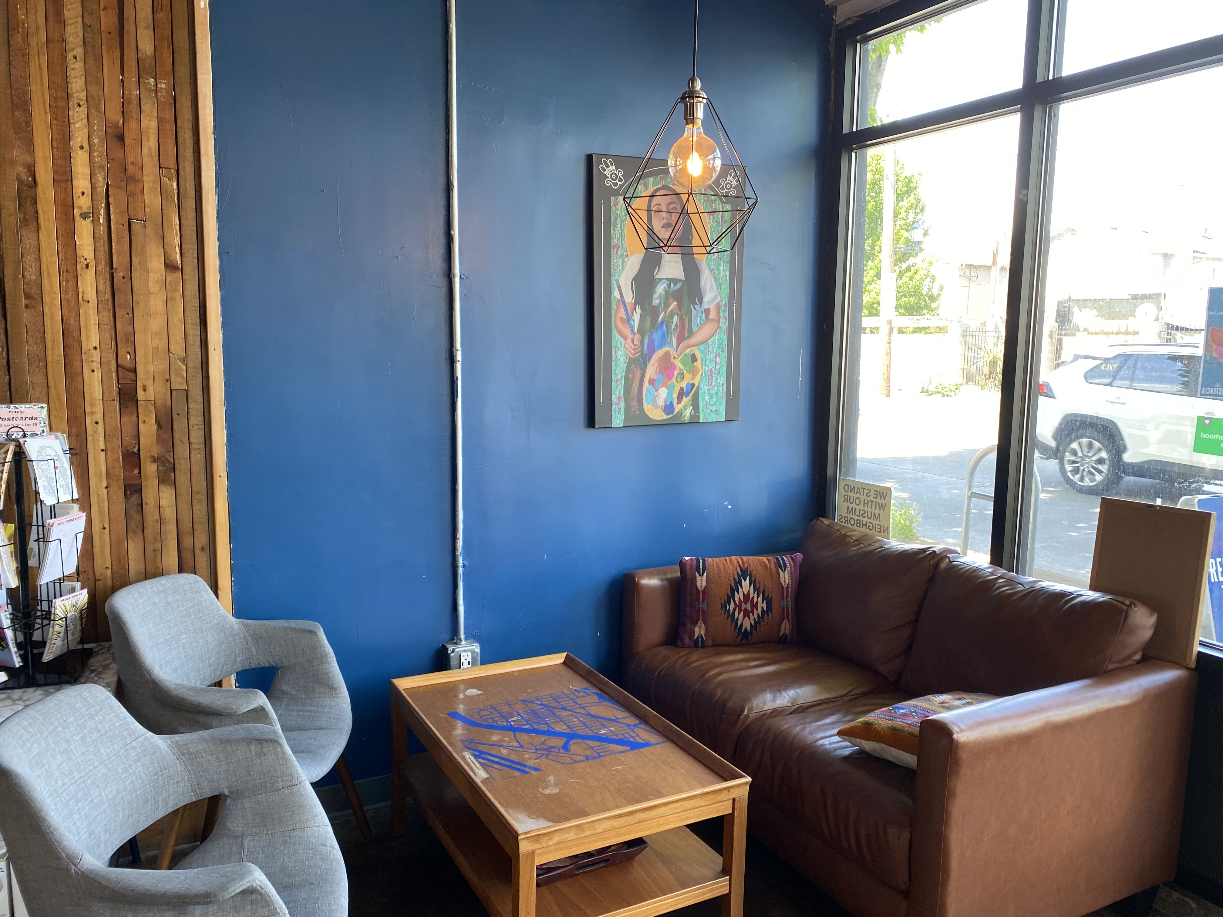 Chairs and a couch around a coffee table with bright blue wall behind them and large window.