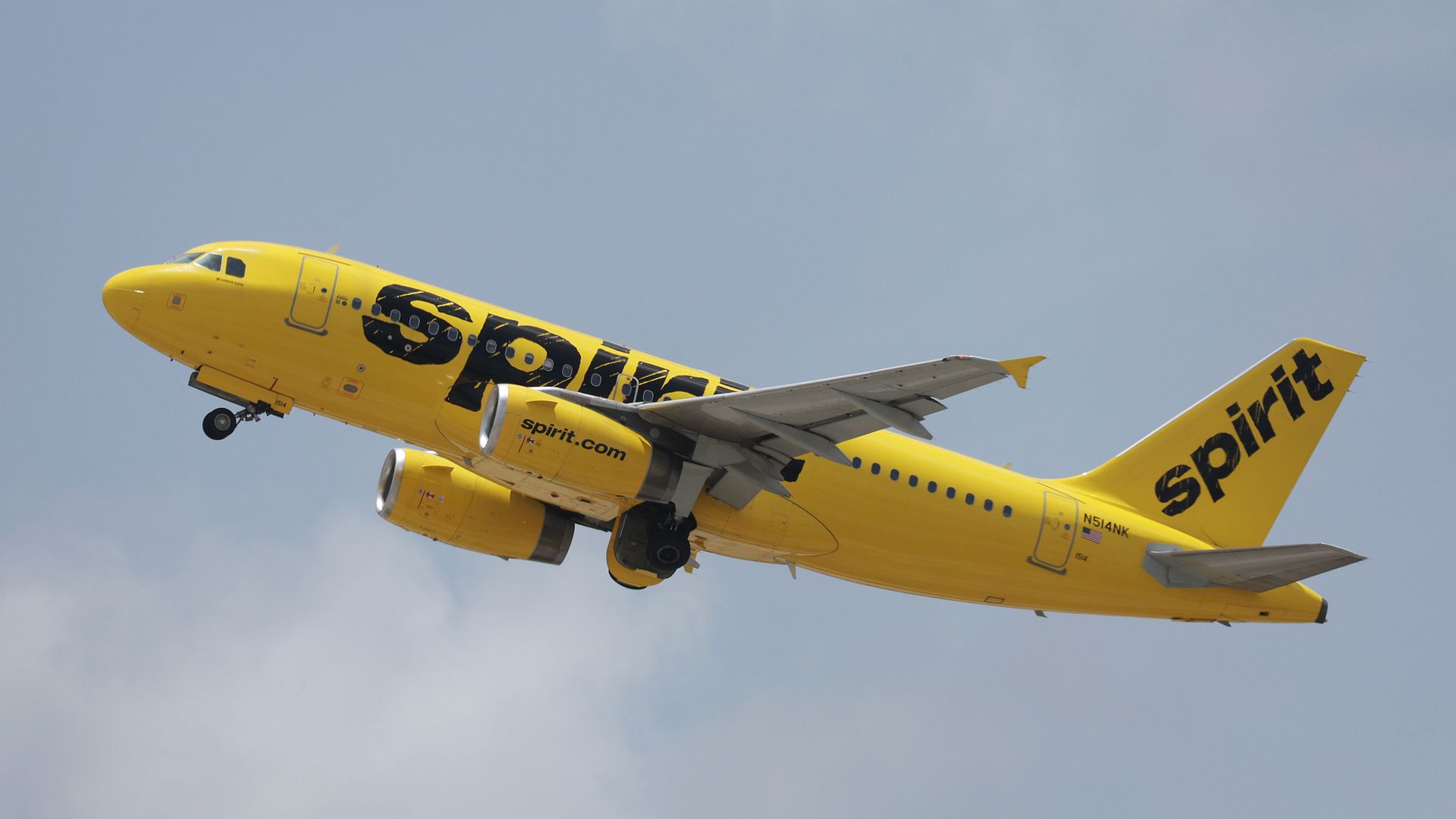 A yellow plane with black lettering flying through the sky