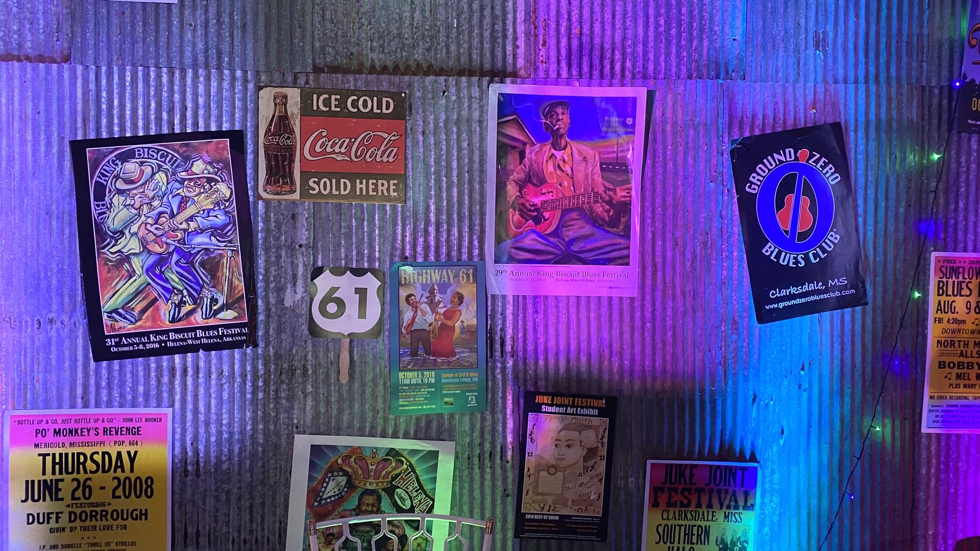 A photo of a corrugated steel wall with posters touting various Blues bands and venues. 