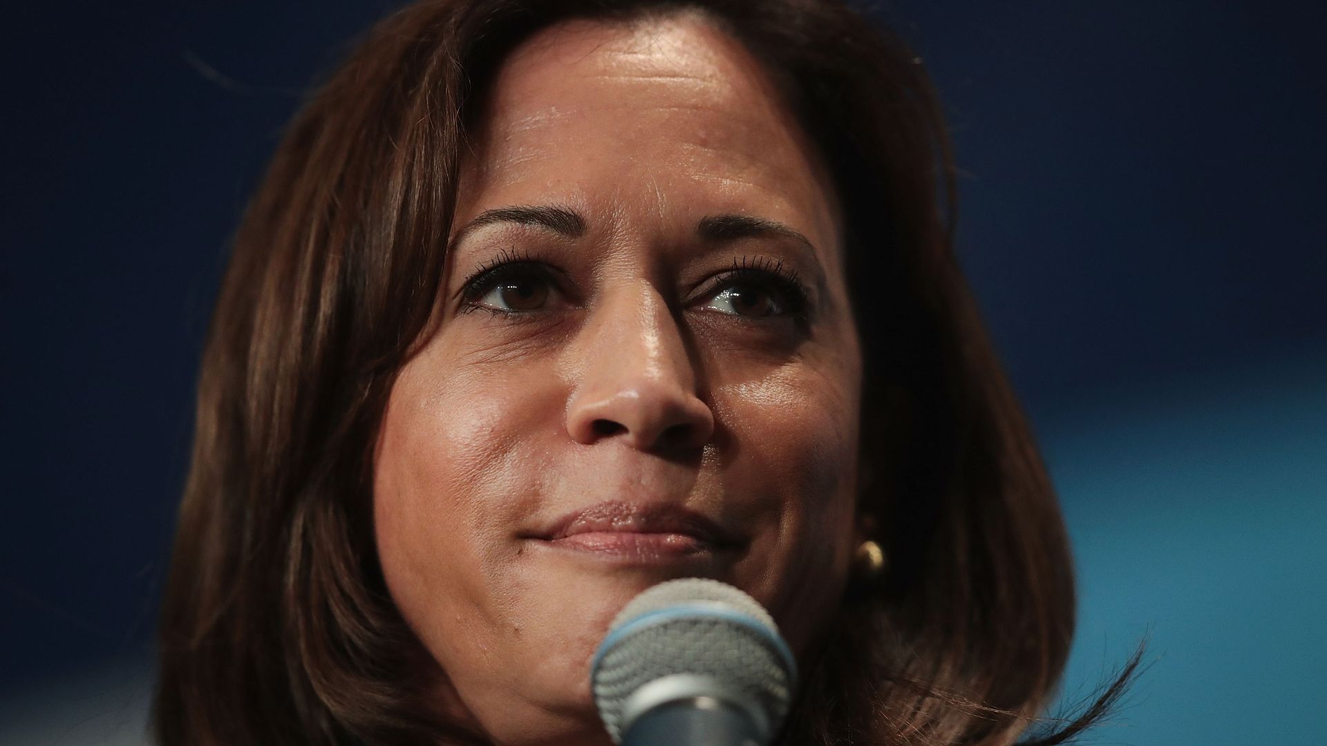 Kamala Harris holding a microphone to her face.