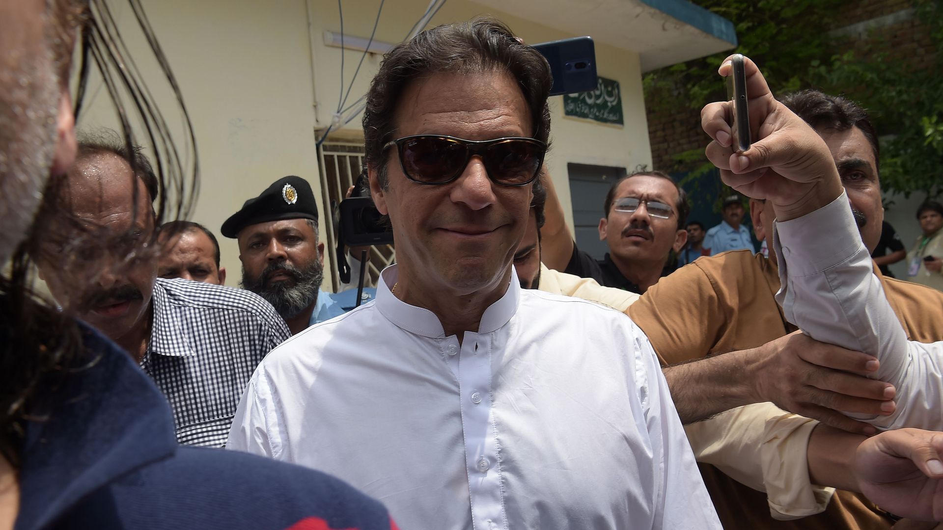 Imran Khan smiling with sunglasses on.