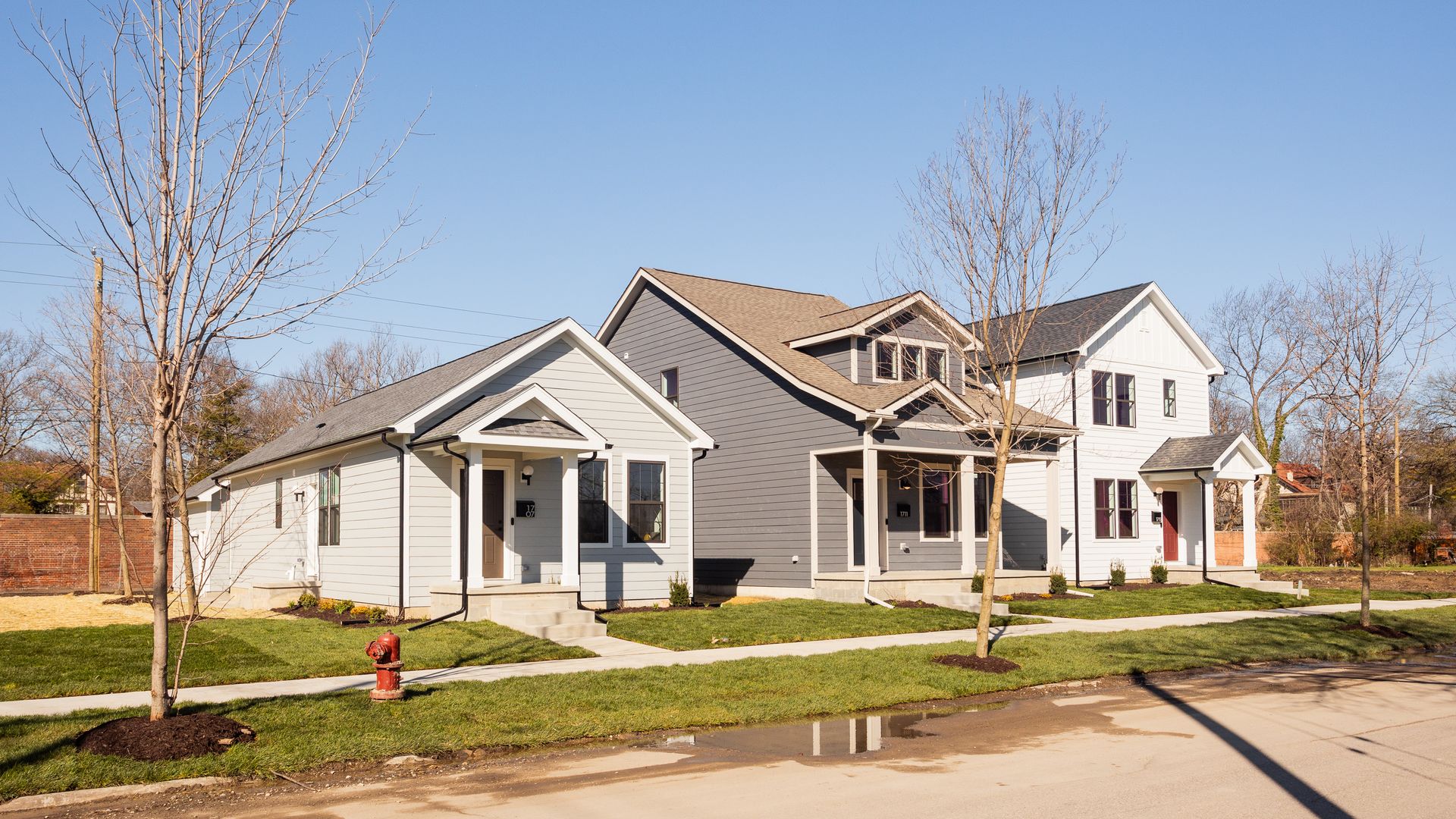 The three homes sit side by side. One is off-white, one is white and one is grey.