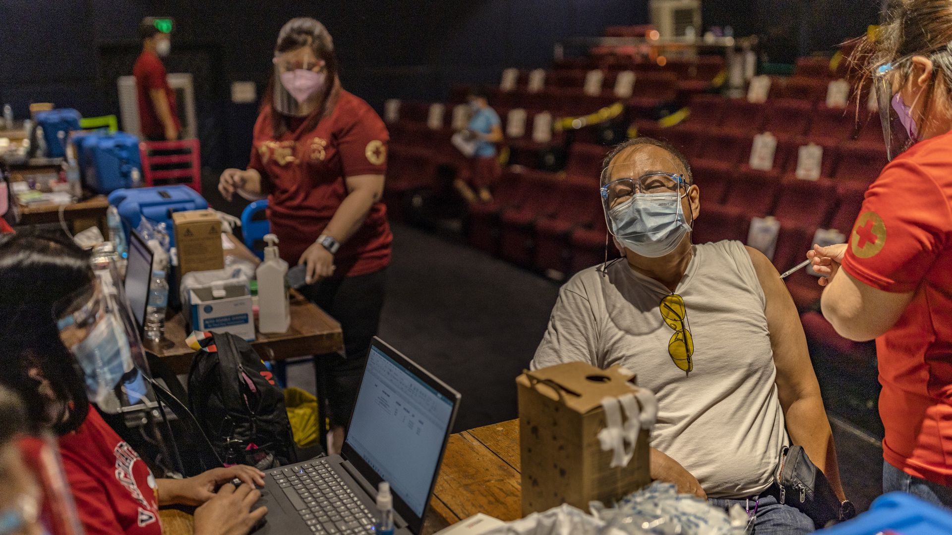 Photo of an older man getting the COVID shot in a mall theatre