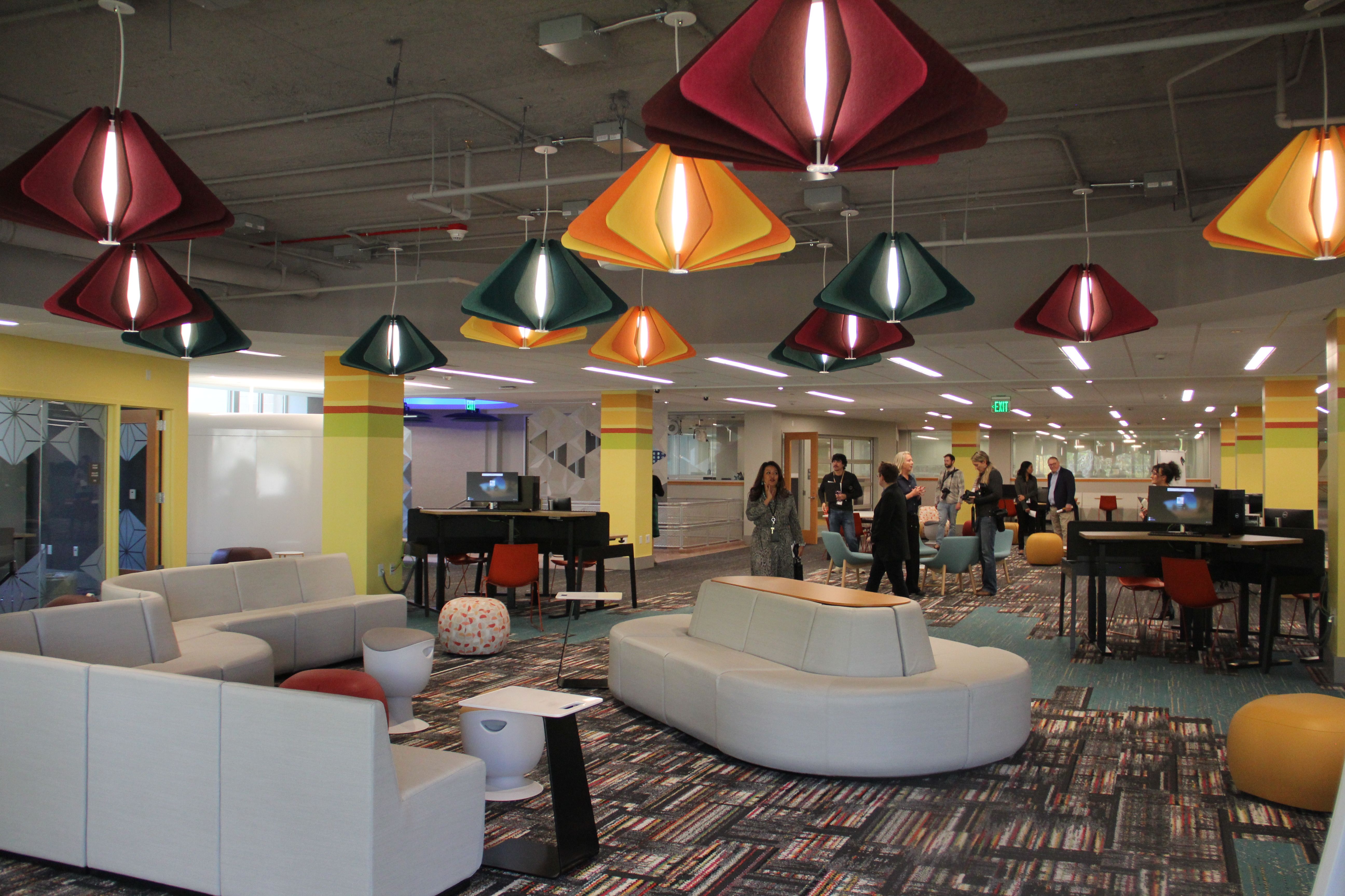 Colorful lights hang over a carpeted floor and space with yellow walls. 