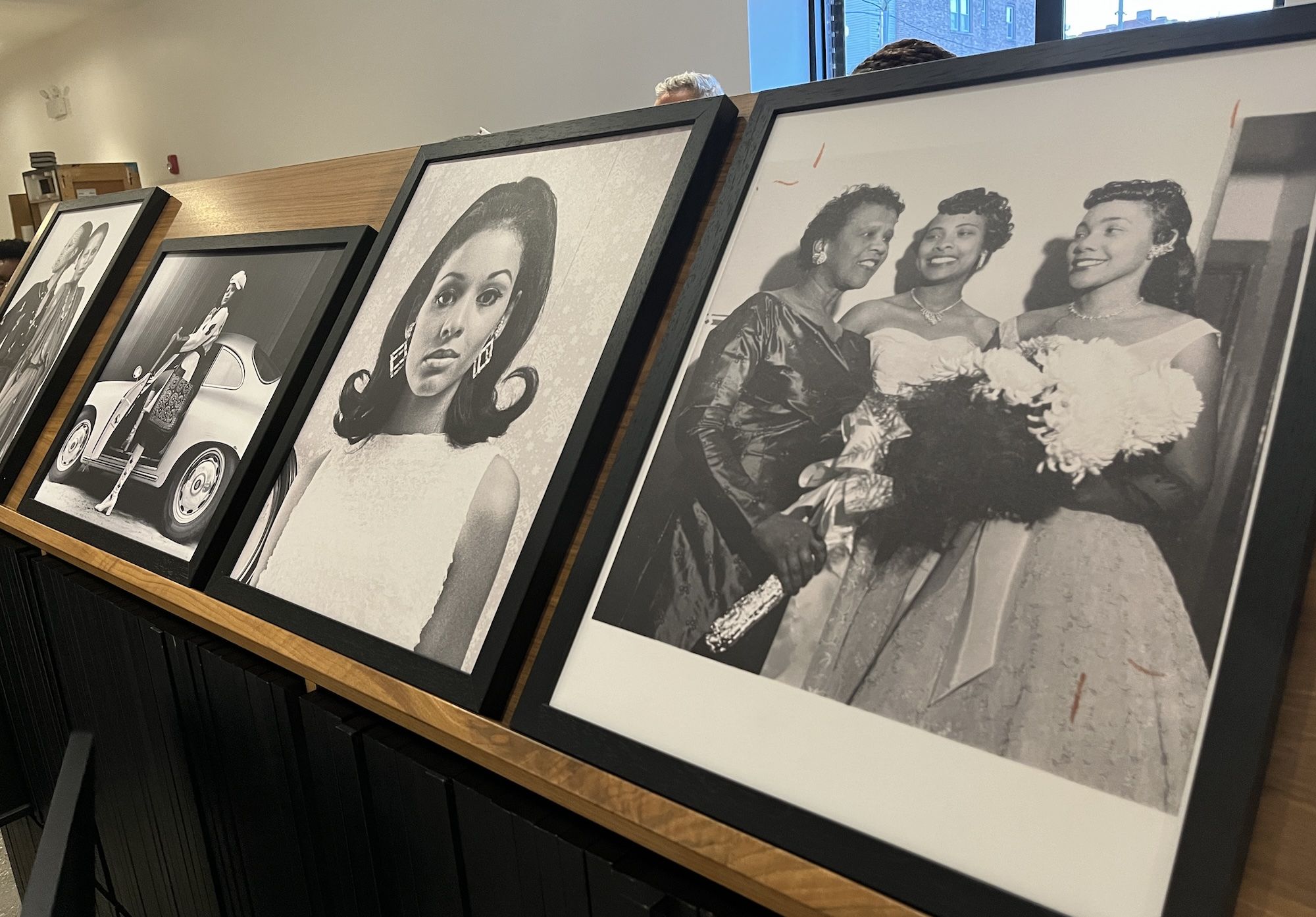 A brown shelf with portraits in black frames.
