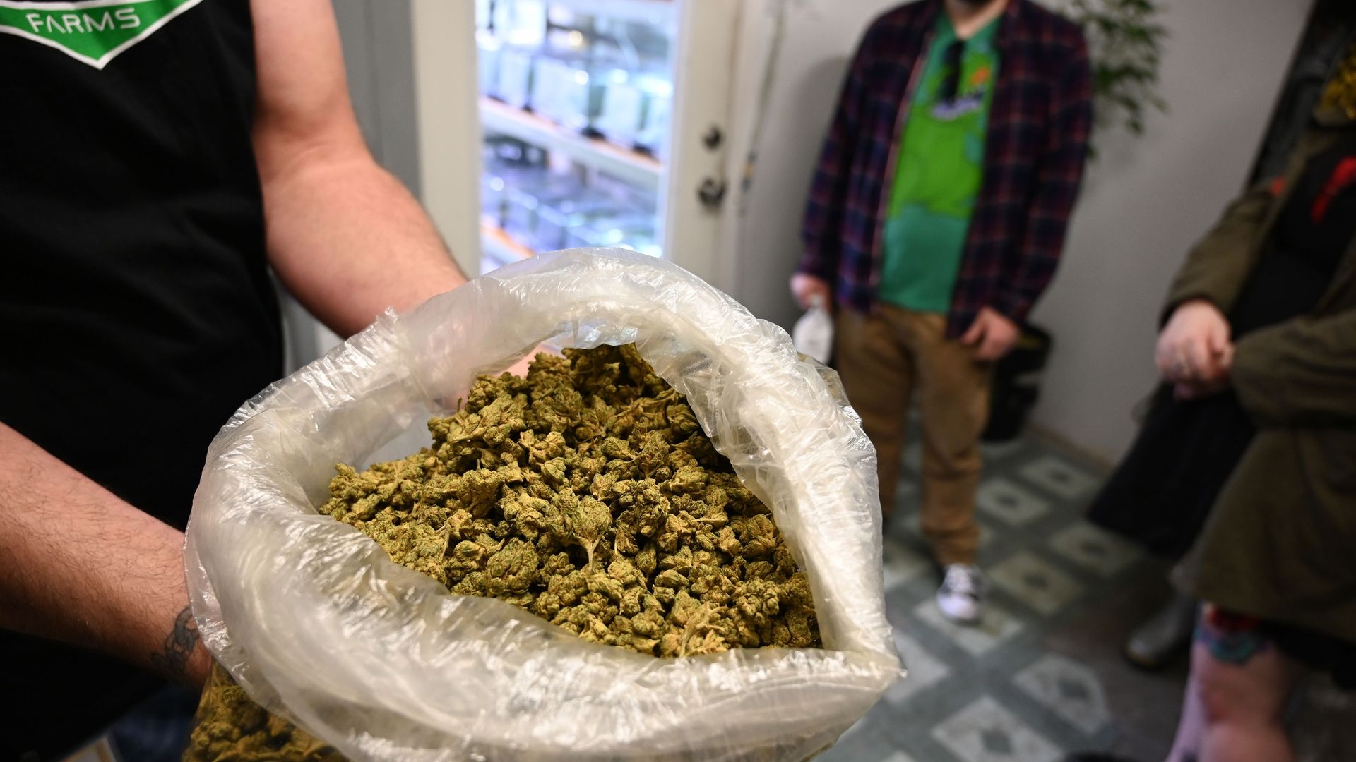 A man holds a bag of marijuana in a store.