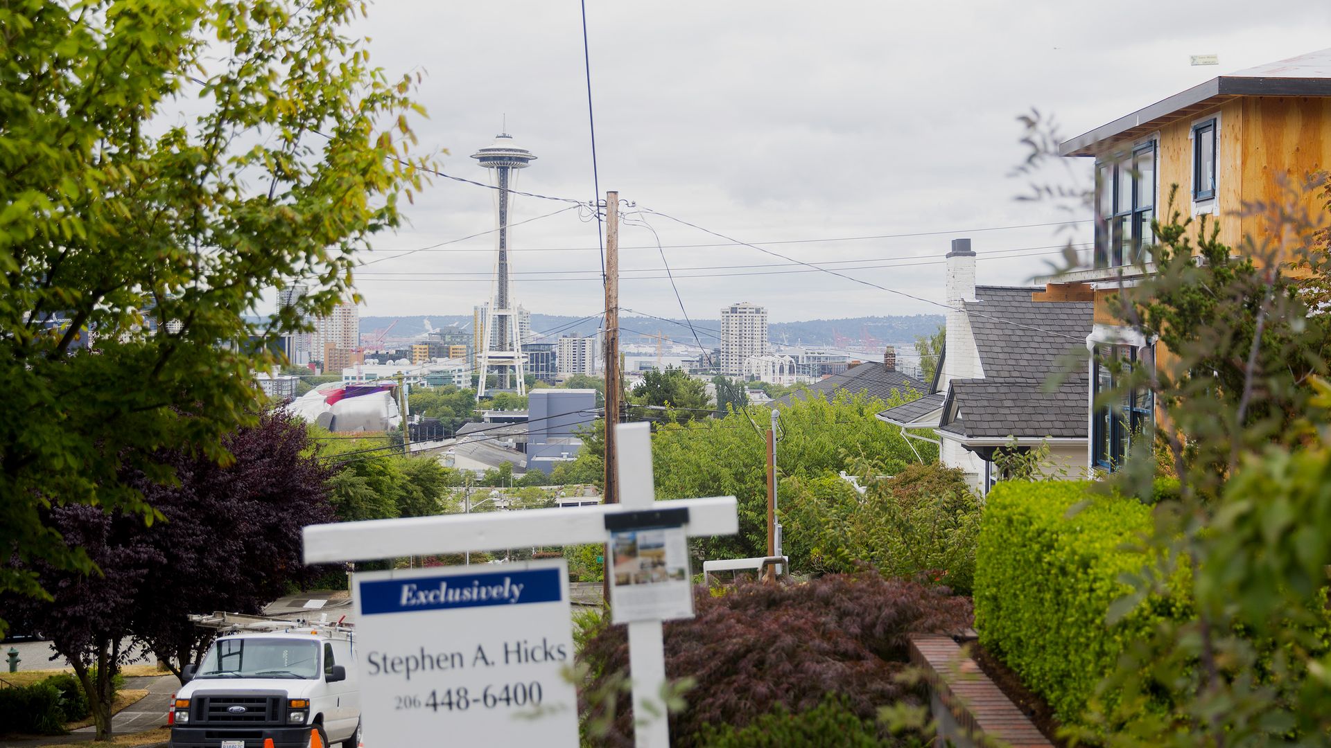 For sale sign in front of house with Seattle Space Needle in background