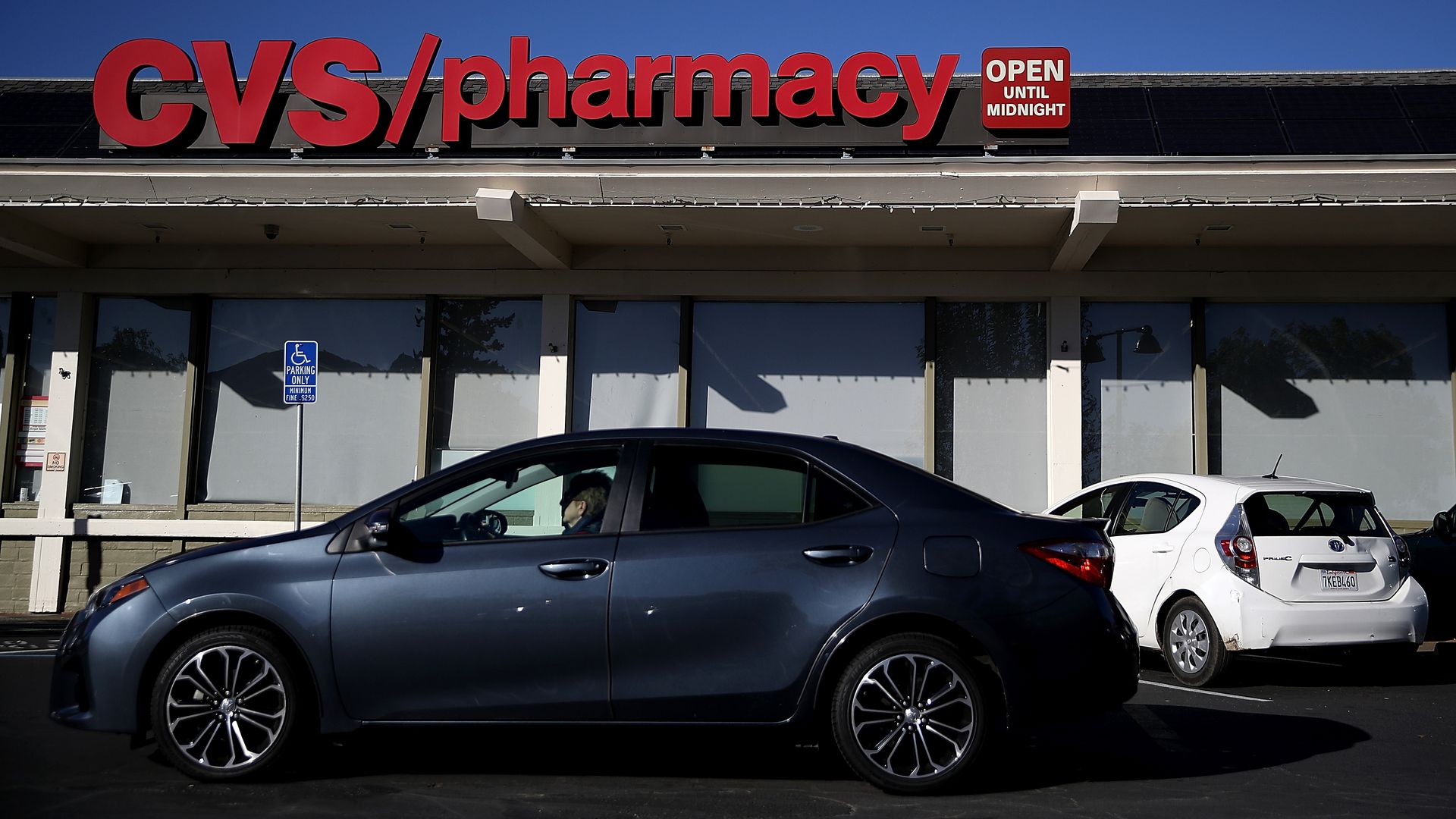 A dark car parked in front of a red CVS/pharmacy sign.