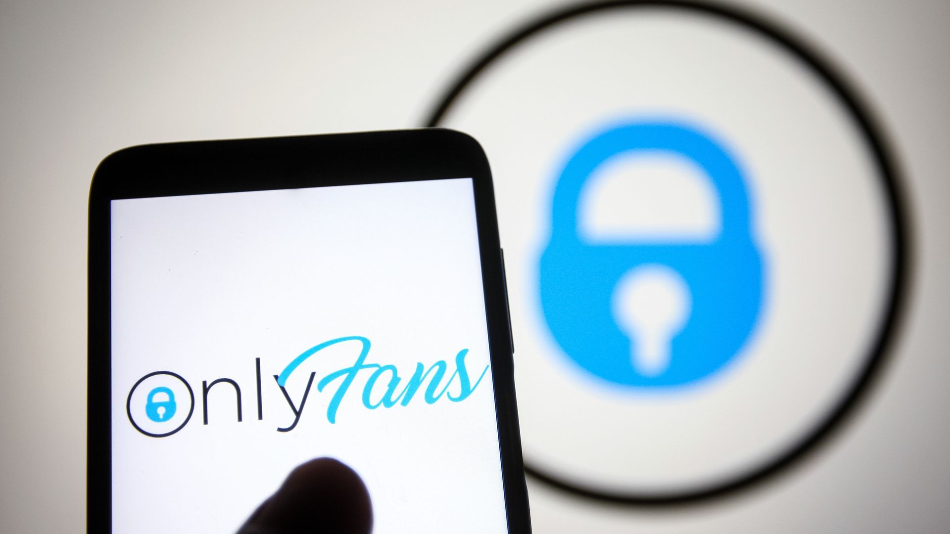 An OnlyFans logo on a phone, with the OnlyFans logo also in the background