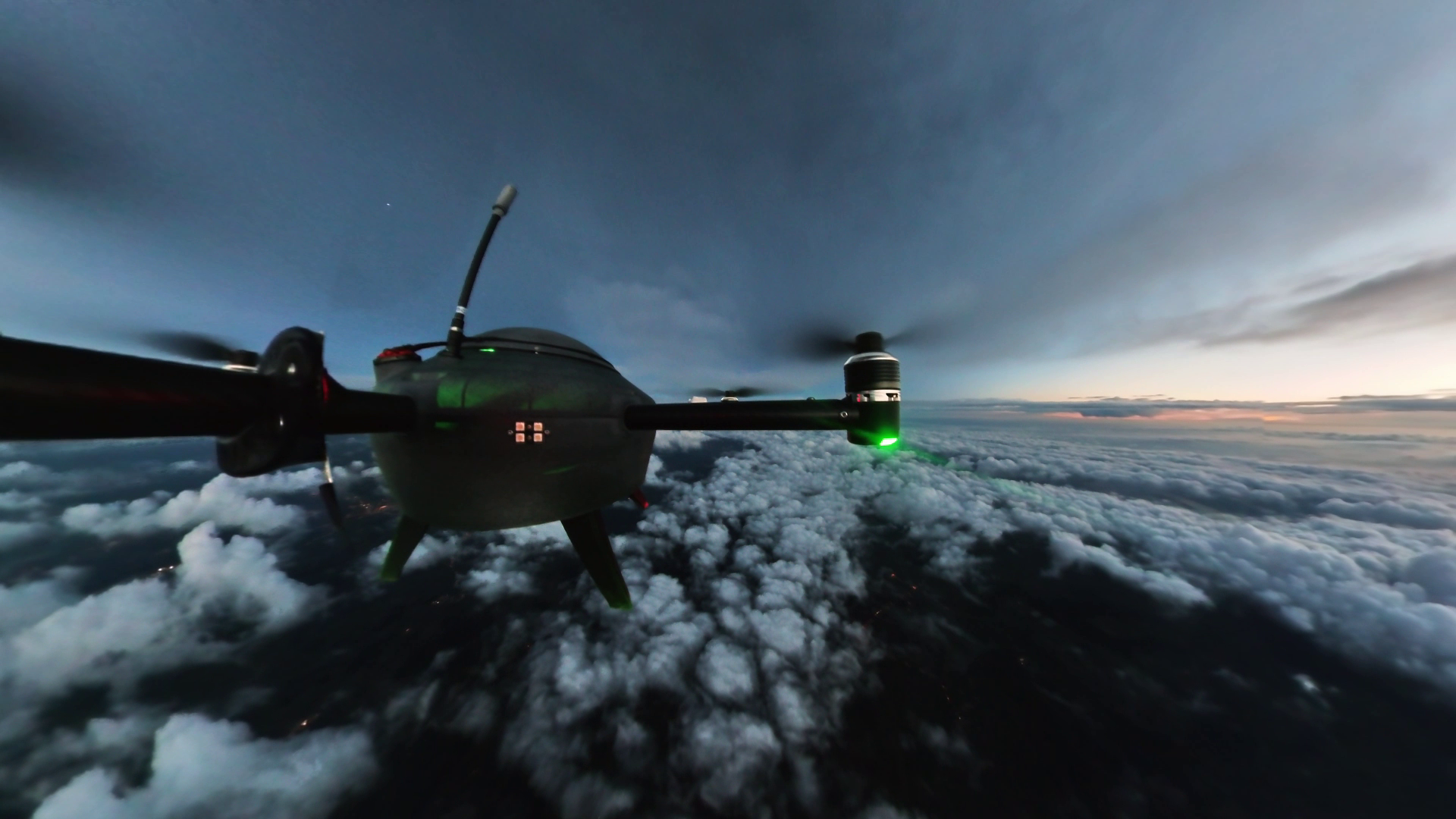 Photo of a drone flying above a layer of clouds against a darkened sky.