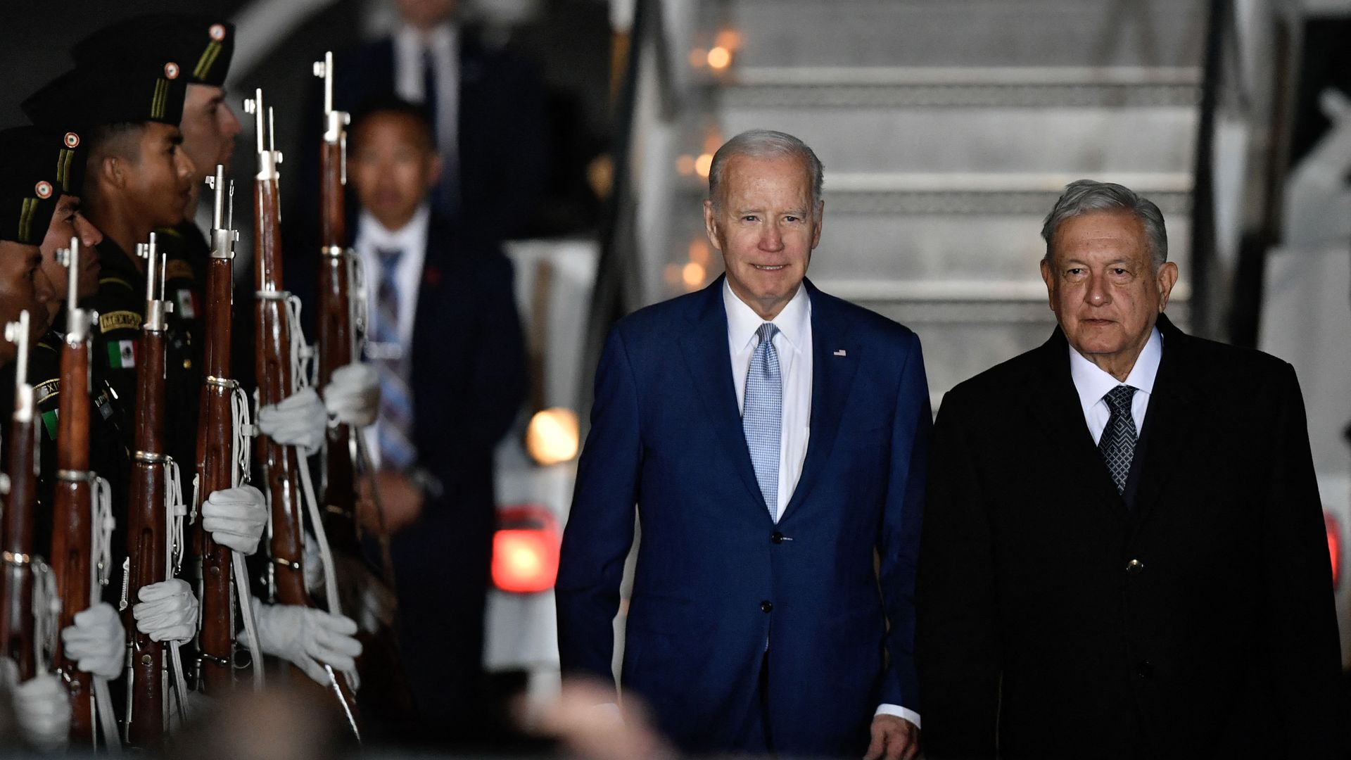 Photo of Joe Biden and Andres Manuel Lopez Obrador standing shoulder to shoulder next to a row of soldiers