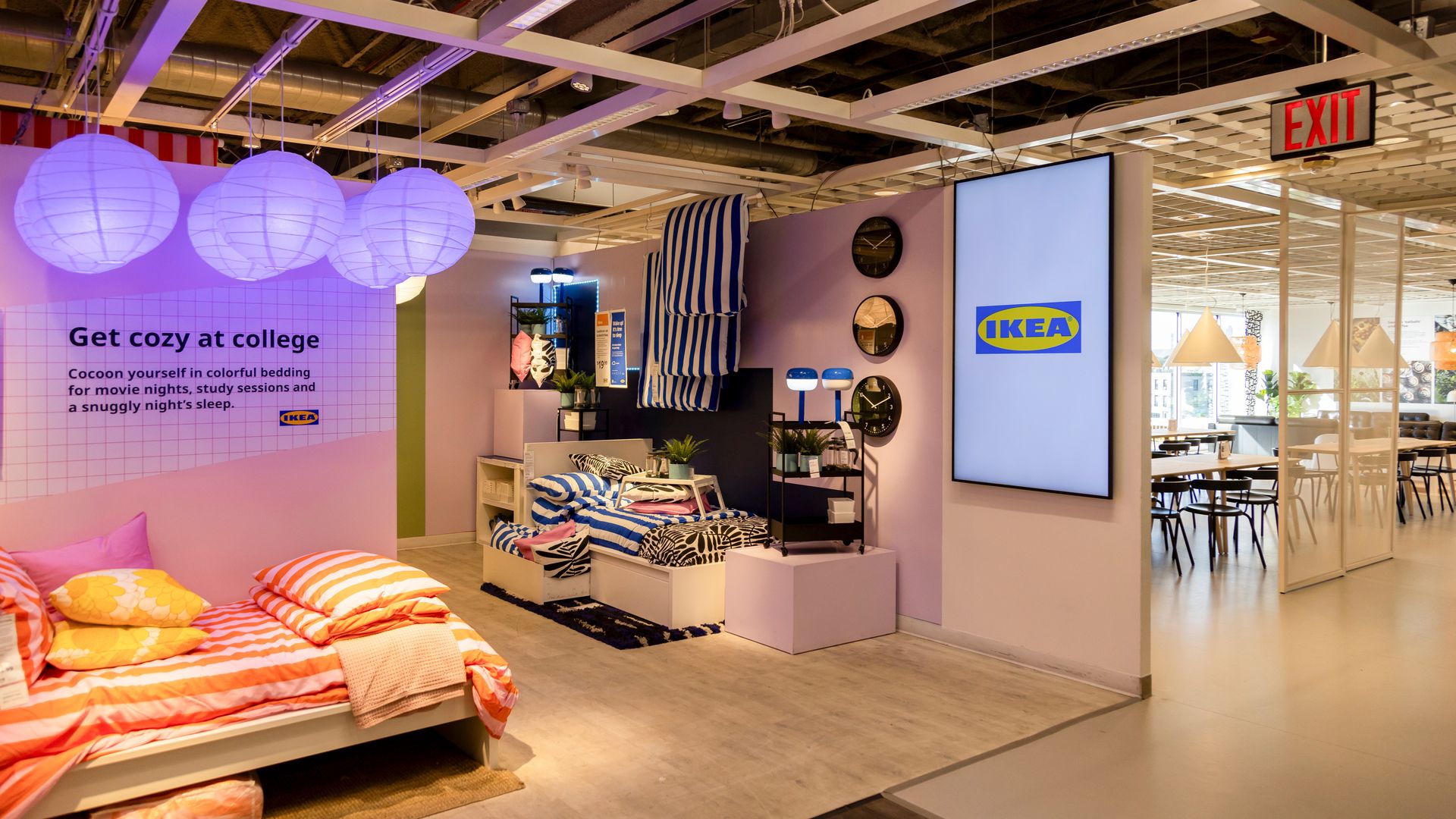 The interior of an IKEA store with a big logo and some bedding meant for college age shoppers