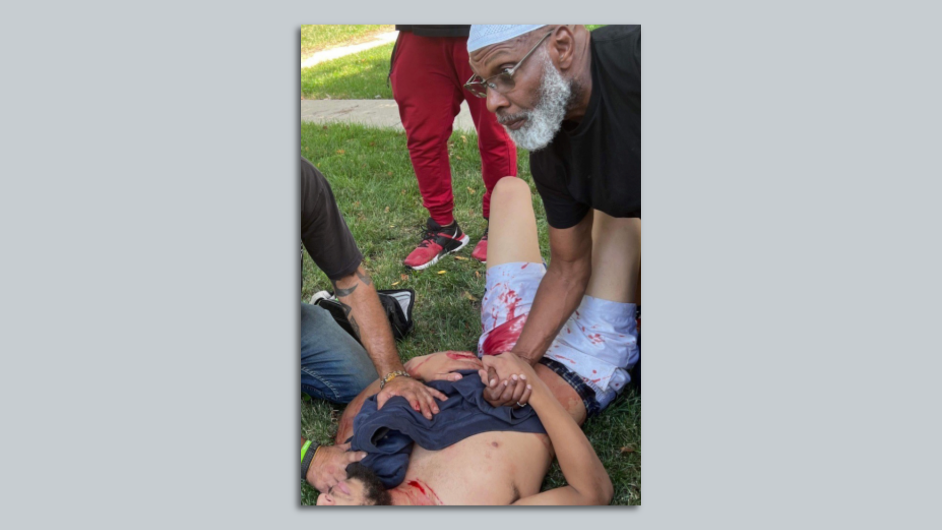 A photo of a man being assisted after a shooting.