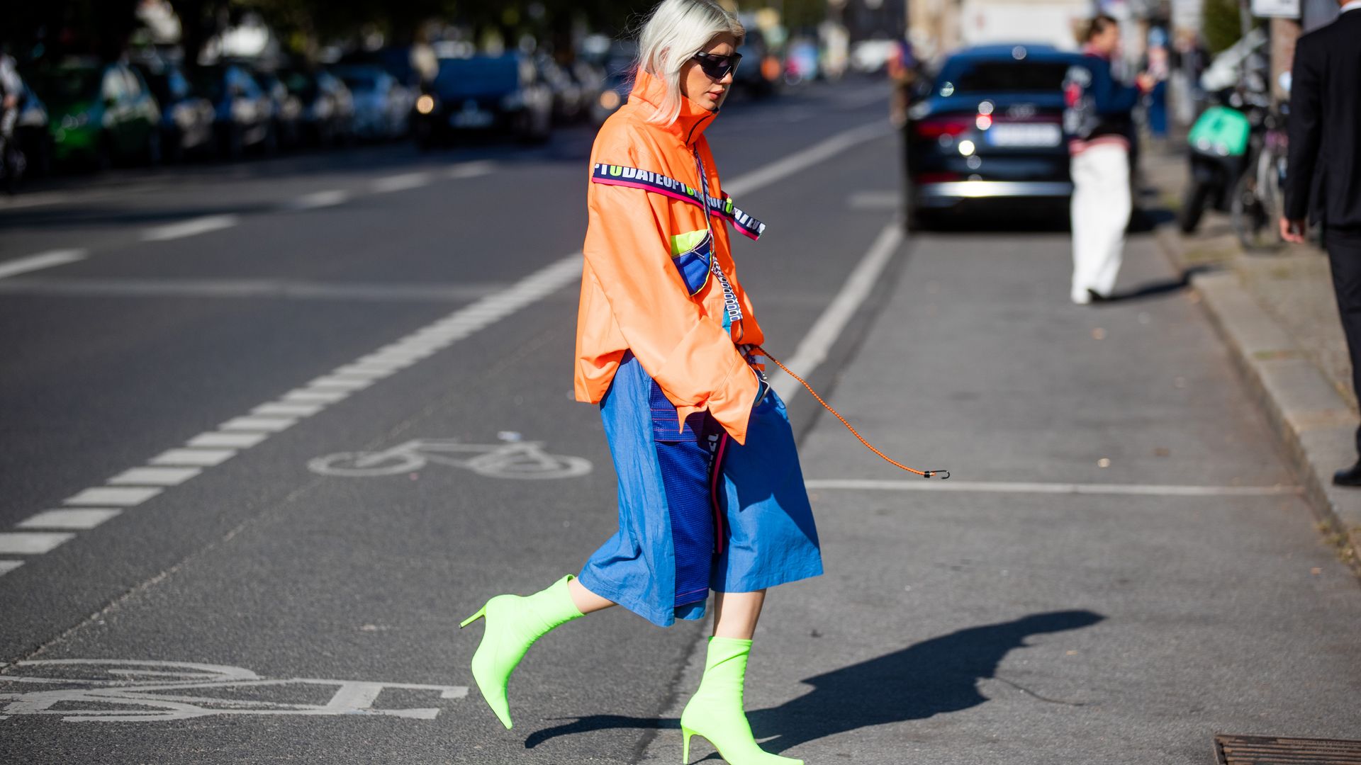 Woman wearing neon clothing and boots during fall fashion week 2021 in Berlin.