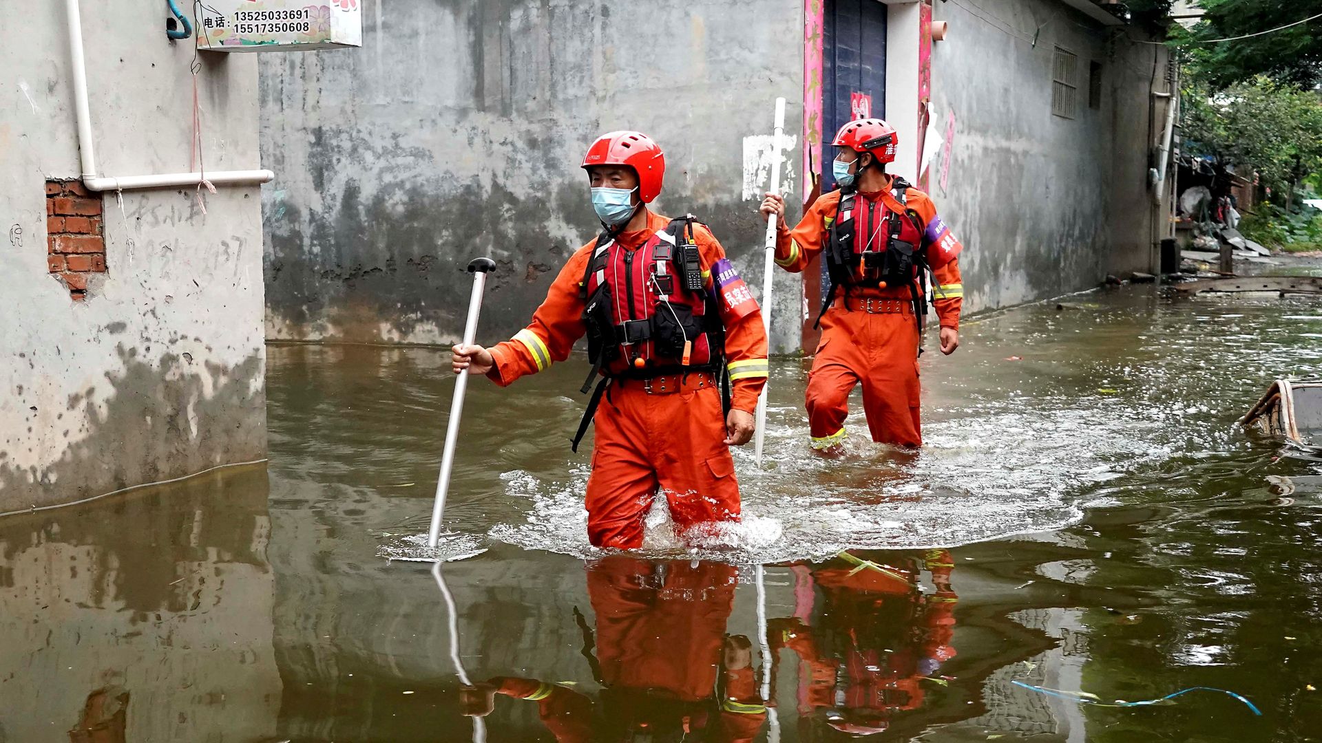 Rescuers search for stranded people while wading through waterlogged area in Weihui City, central China's Henan Province, July 28, 2021. 