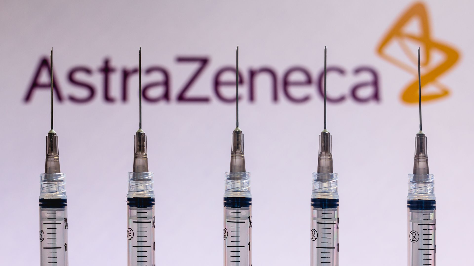The AstraZeneca logo seen behind several syringes 