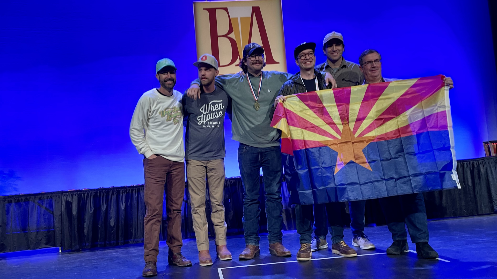 A group of men on stage holding an Arizona flag.