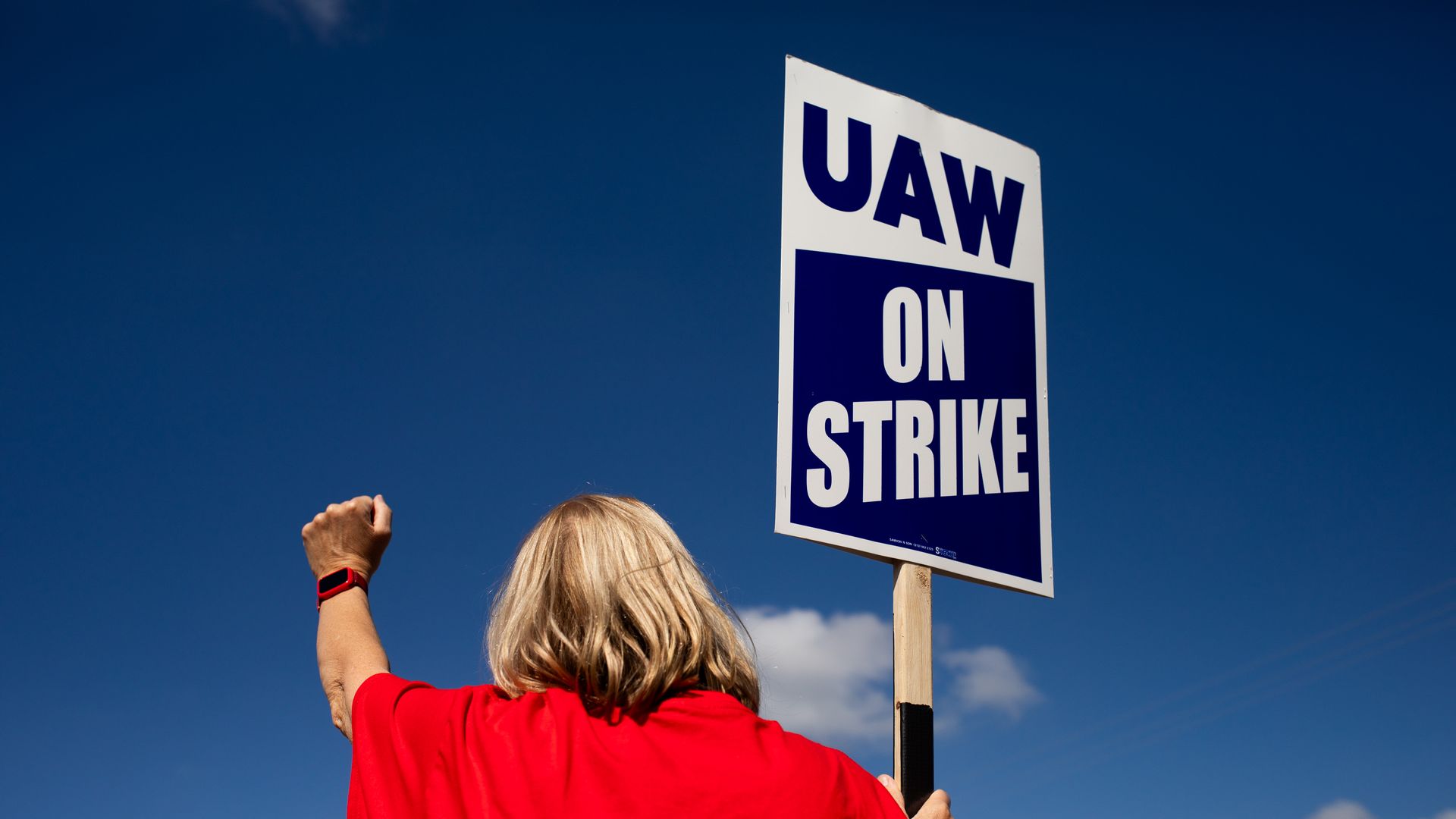 A UAW worker holds up fist with a "UAW on strike" sign.