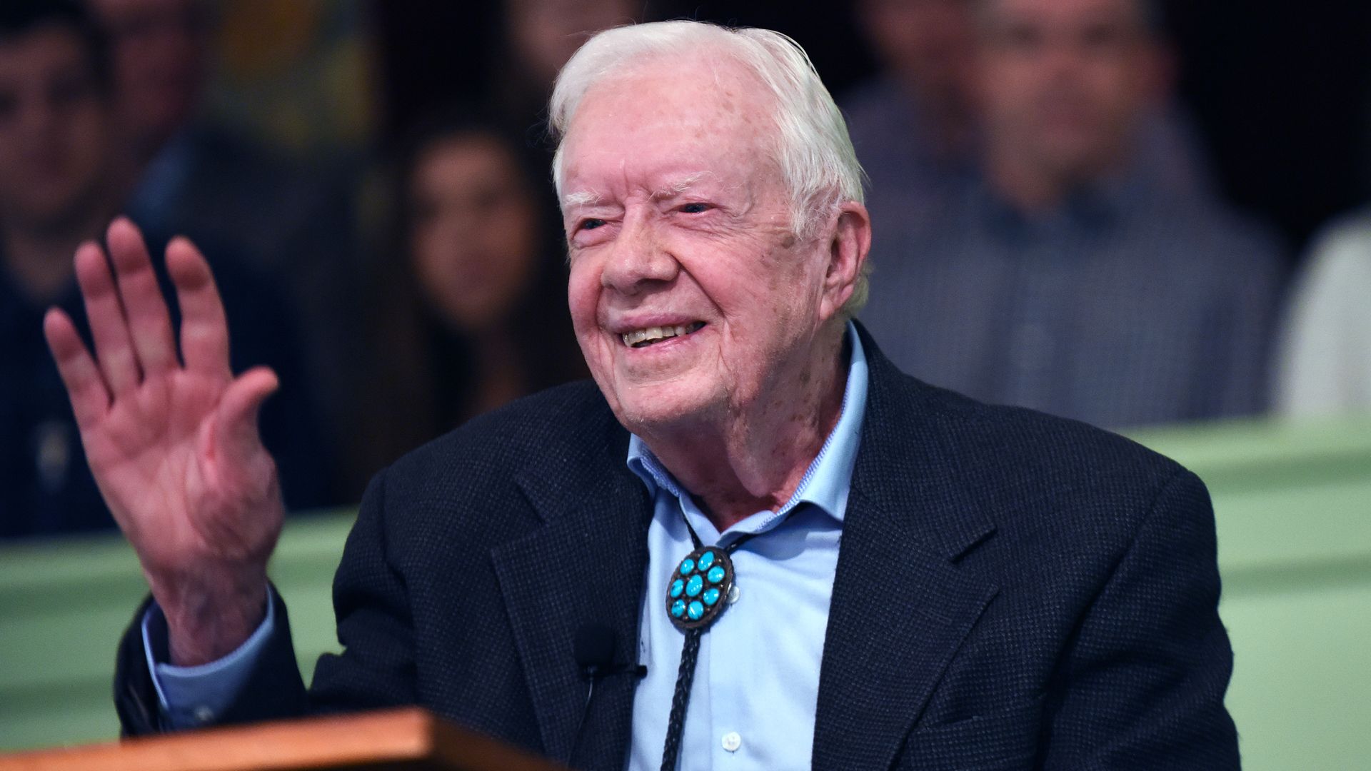 In this image, Jimmy Carter sits and waves