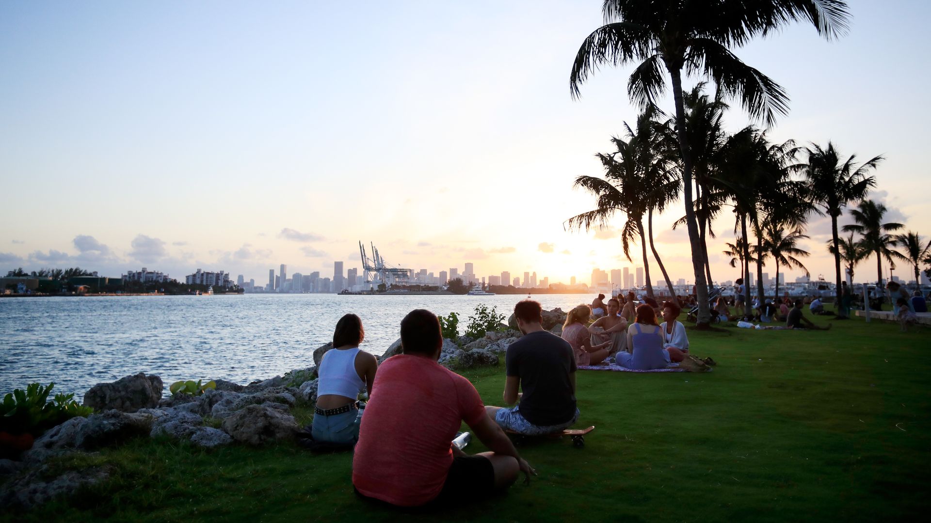 Parkgoers in South Beach watch the sunset by the water.