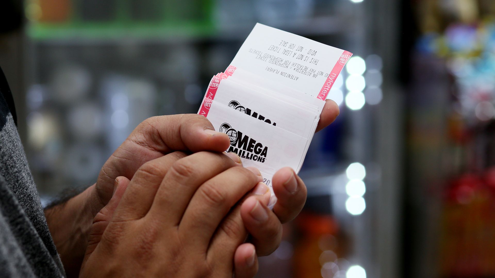 Hands holding Mega Millions lottery tickets