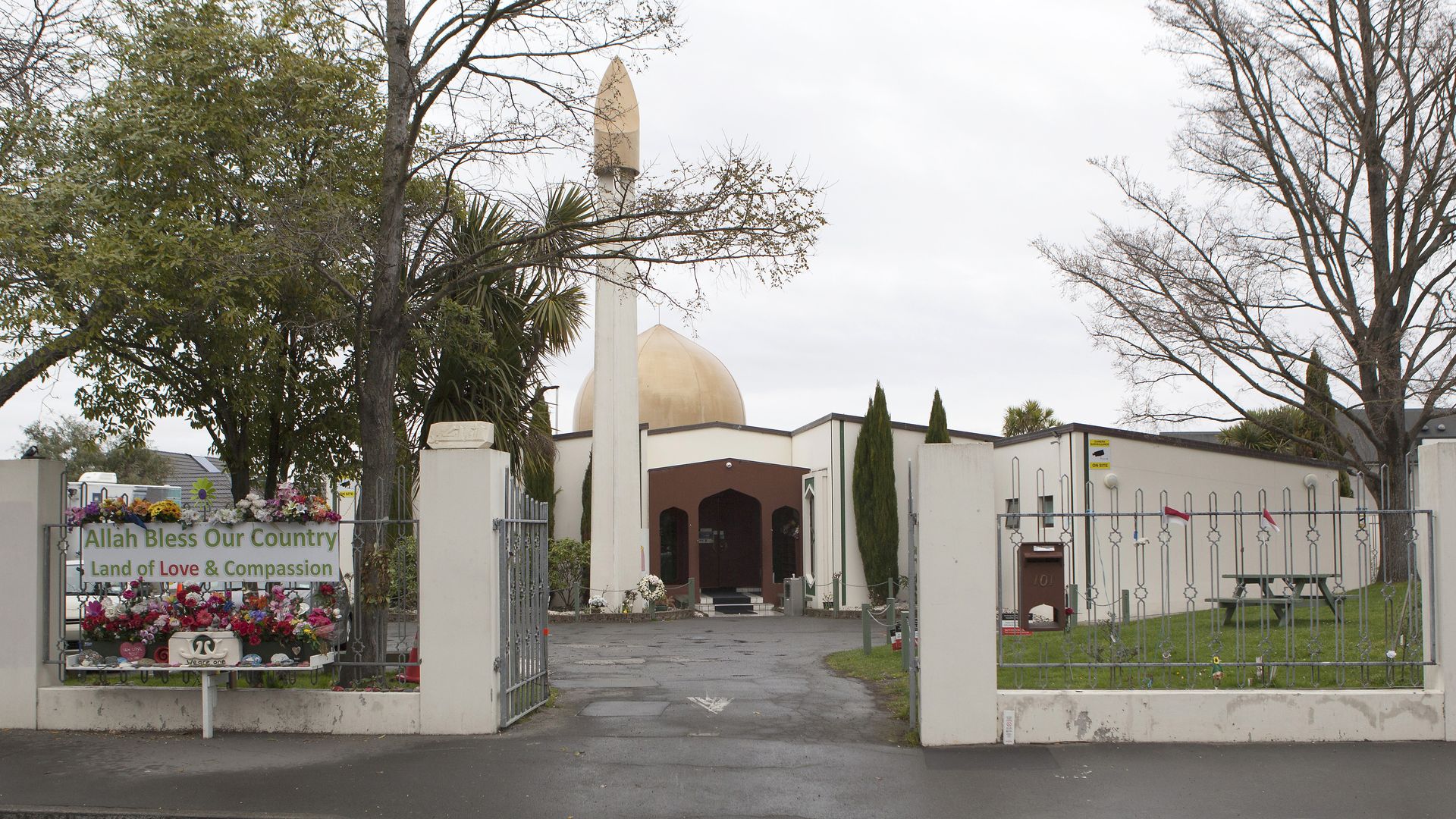 In this image, the front gate of the mosque targeted in the Christ Church shooting is seen with a sign that says "Allah Bless our Country"