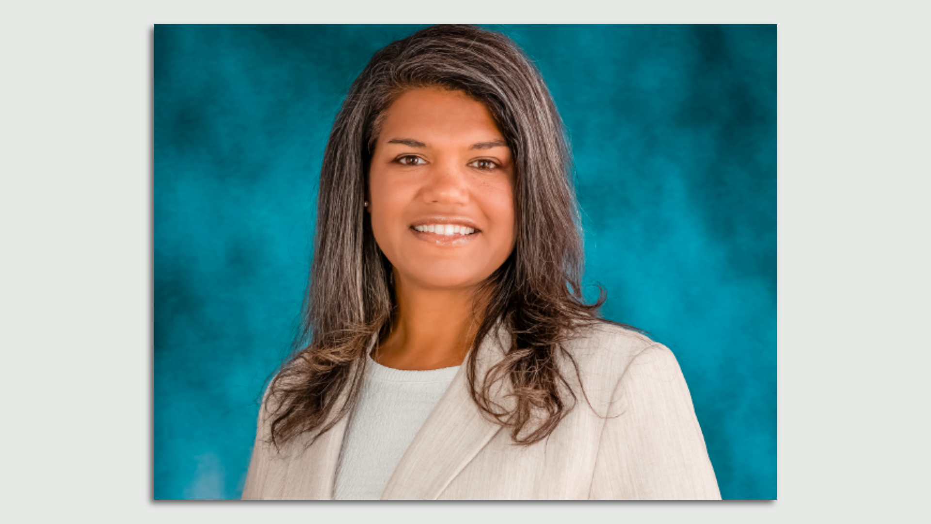 Headshot of a woman in a suit on a blue background