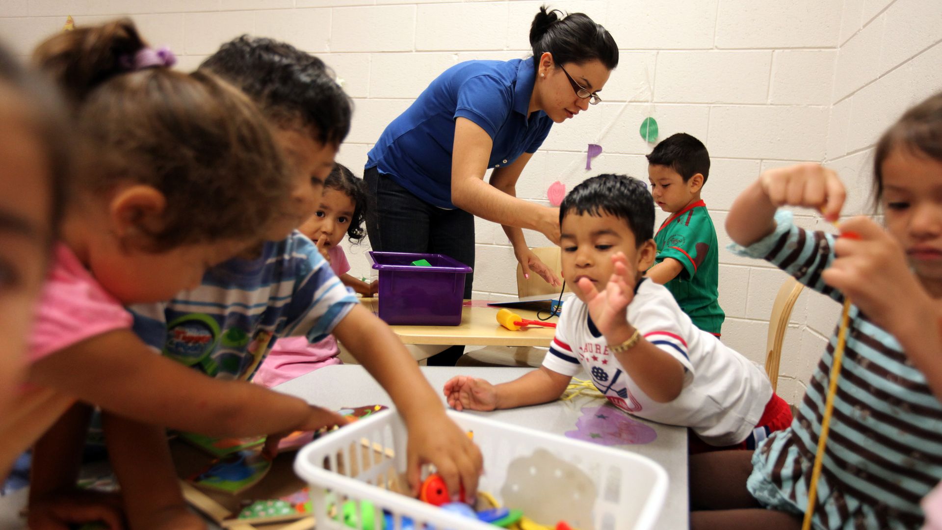 young kids playing at a table in a classroom.