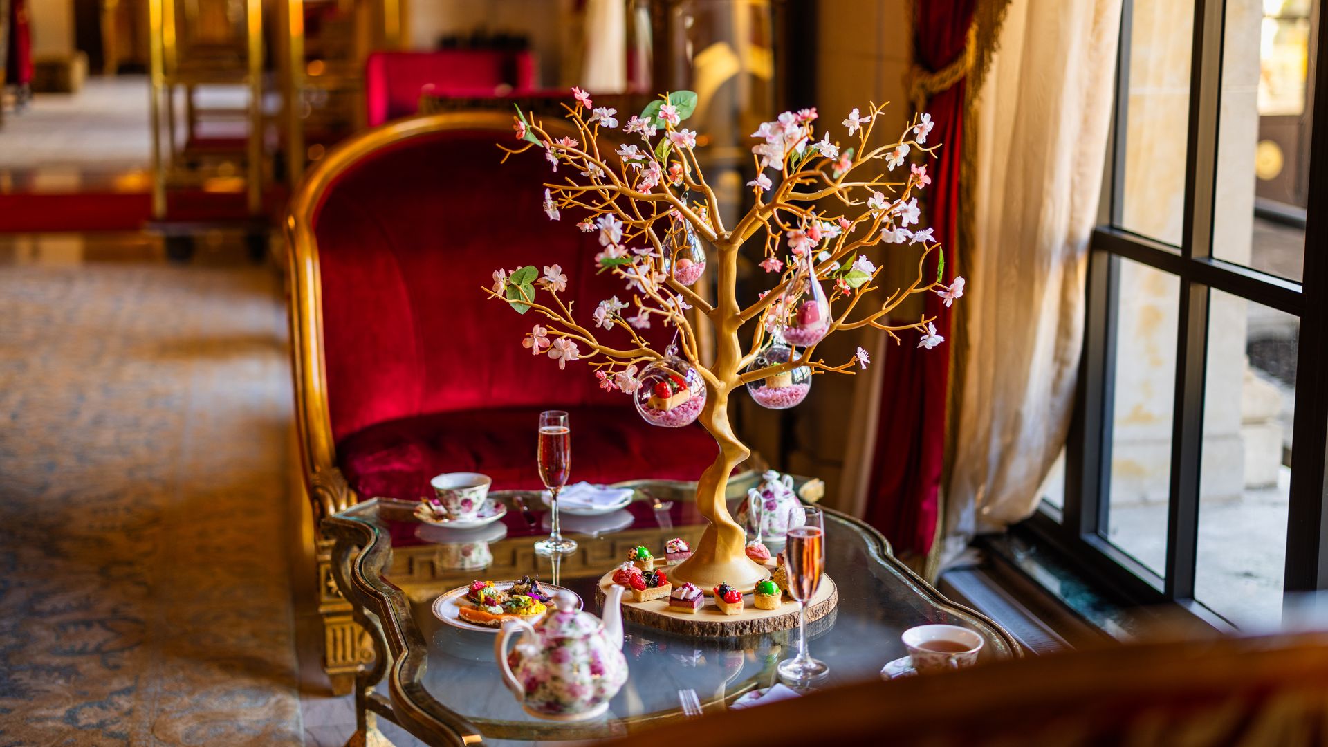 A decorative tree in the middle of a table with Champagne flutes and a red chair in the background