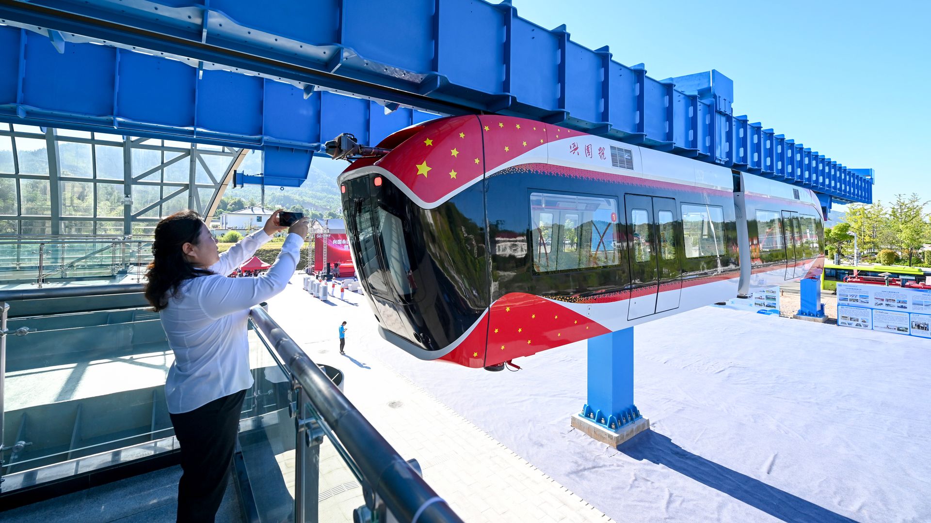 A woman takes photos of China's first permanent maglev-suspension monorail.