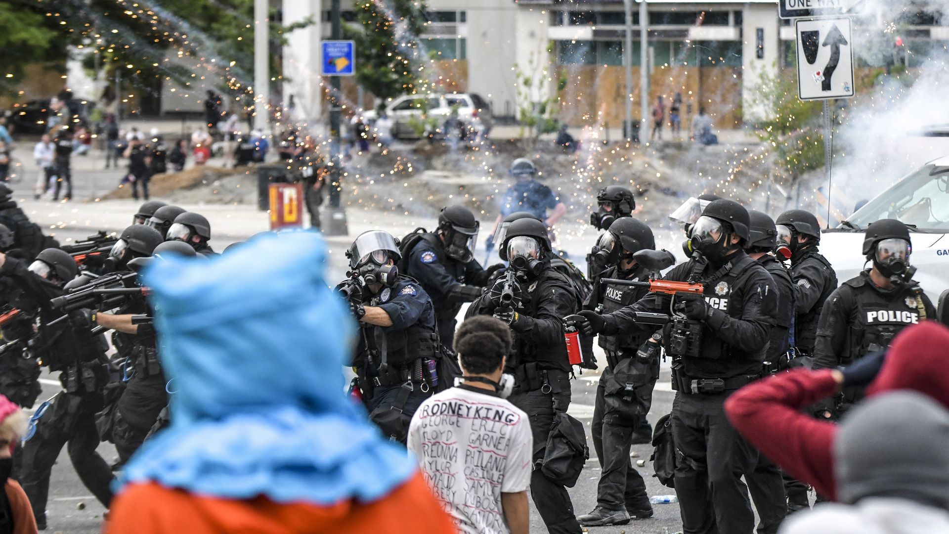 A firework explodes behind a line of police officers next to the Colorado State Capitol