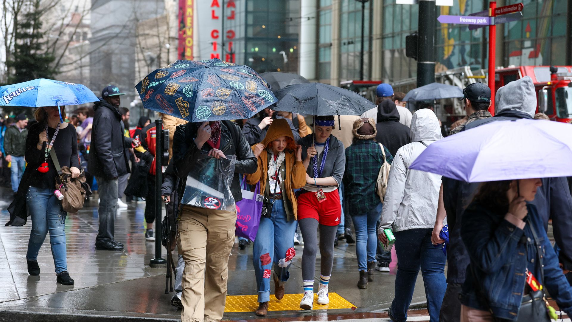 A crowd of people with colorful umbrellas walk on a street in Seattle. 