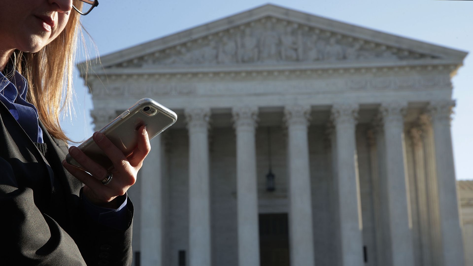 A woman checks her cell phone as she waits in line to enter the U.S. Supreme Court