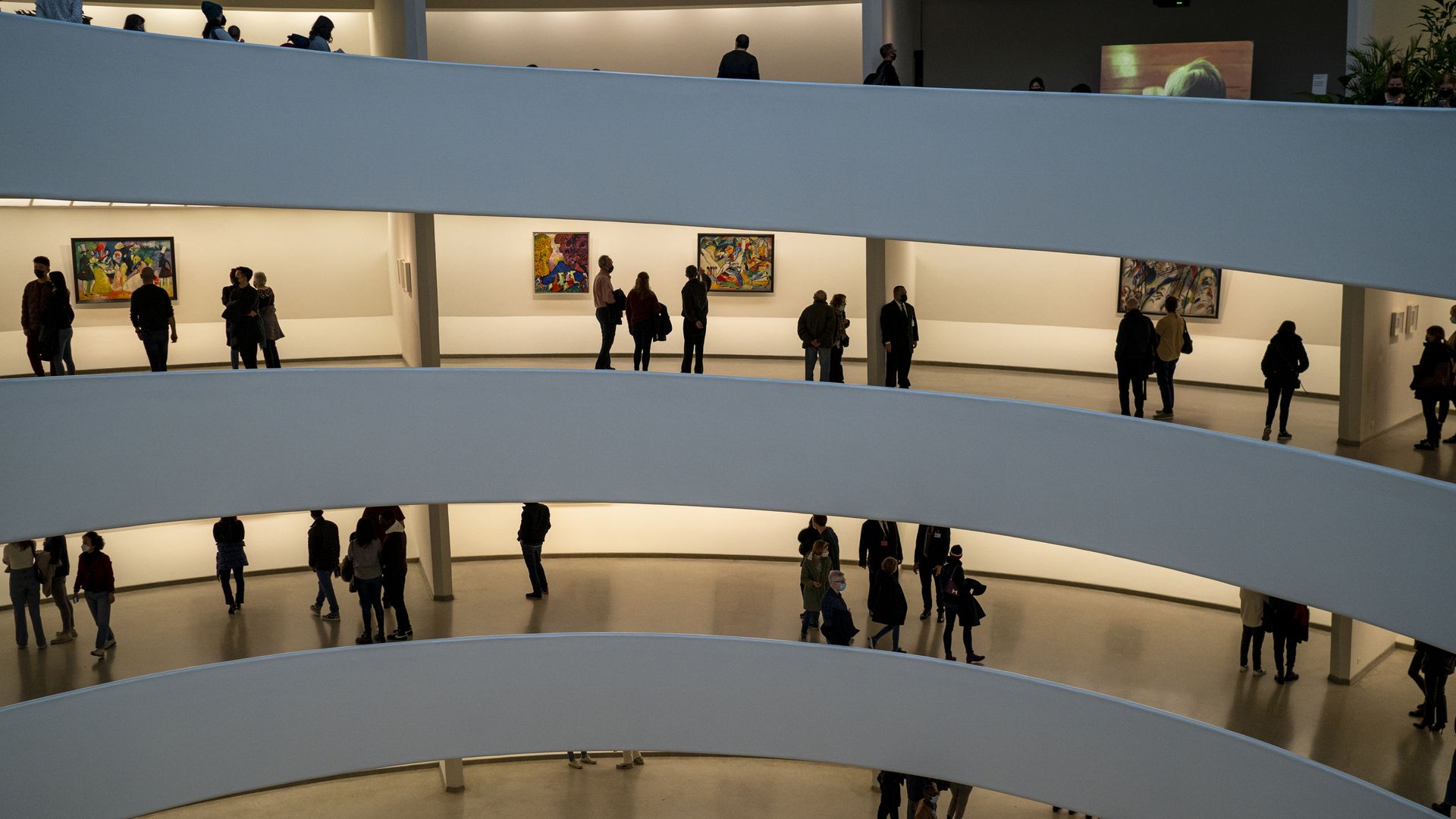 Photo of people milling about several floors of art galleries