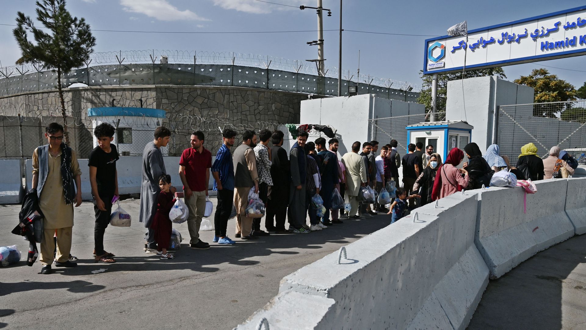 Afghans, hoping to leave Afghanistan, queue at the main entrance gate of Kabul airport in Kabul on August 28, 2021,
