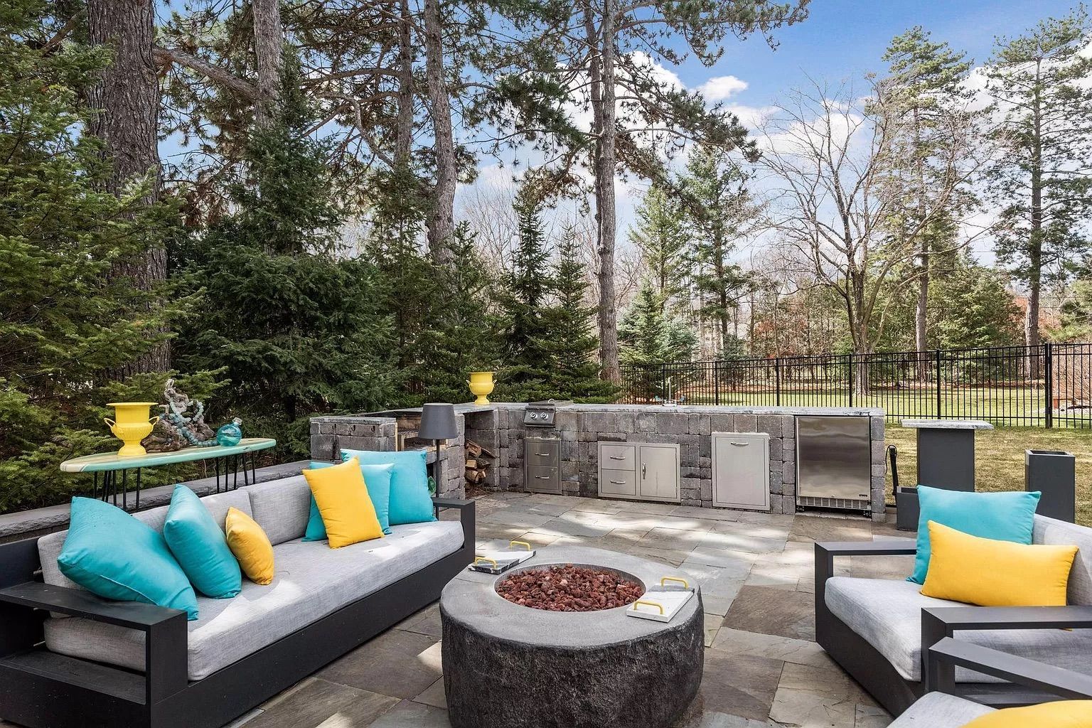 An outdoor patio with gray couches and blue and yellow pillows.