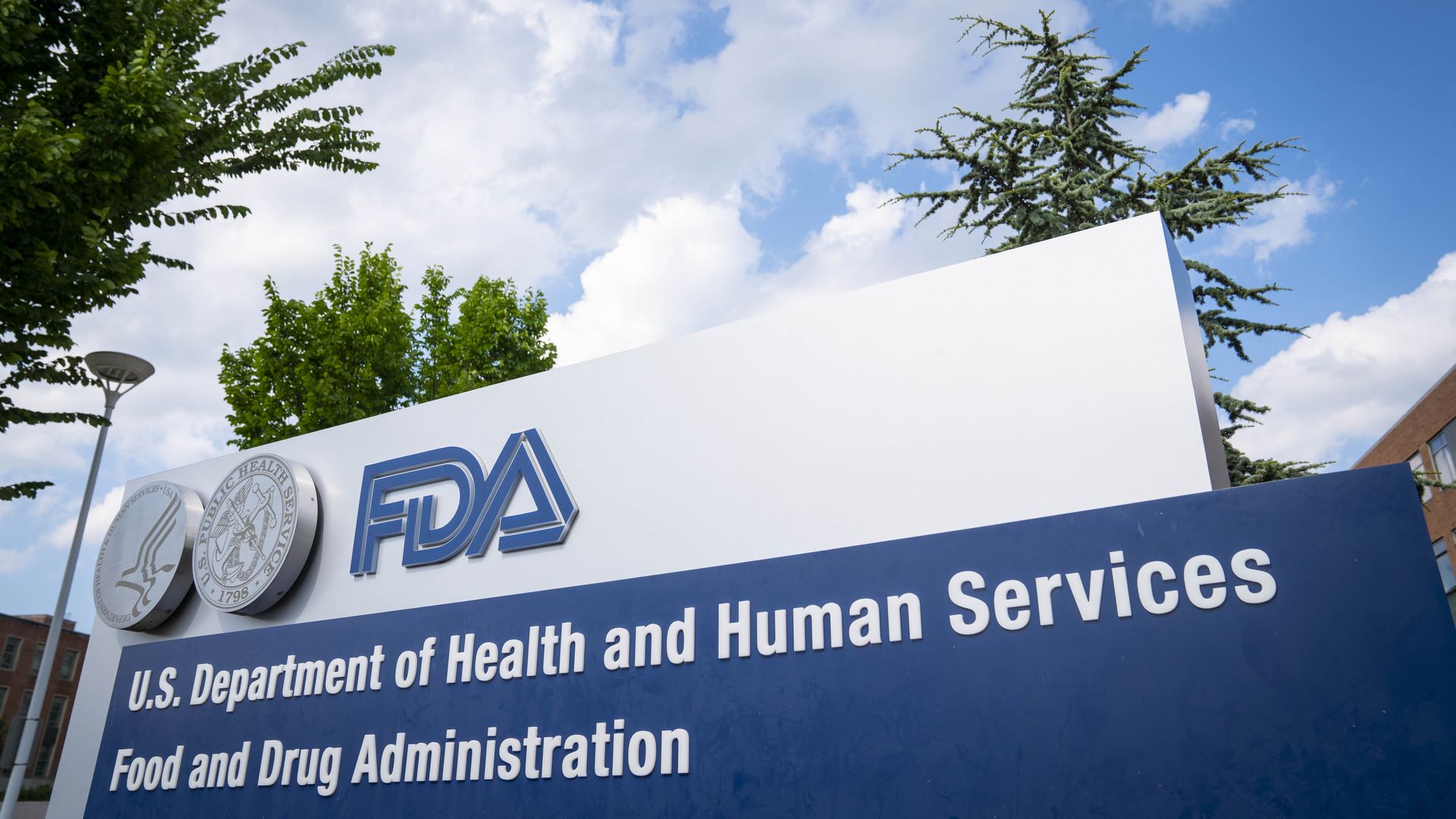 Image of the FDA sign in front of a cloudy blue sky and trees