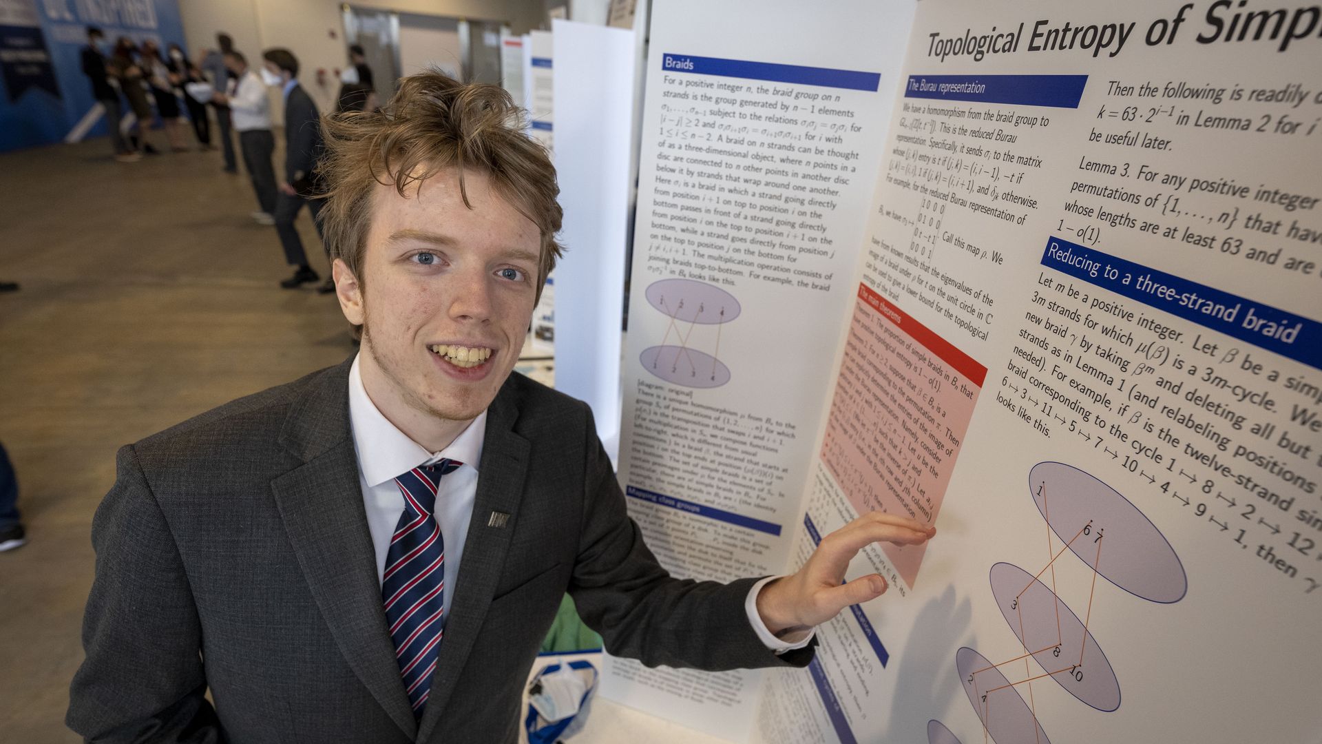 A young man standing next to his science project