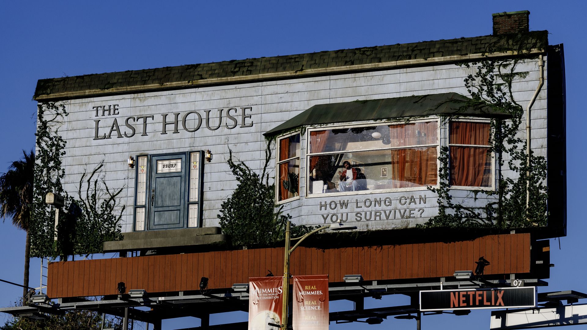 A man living in a billboard as a part of a Netflix promotion for the upcoming film "The Last House" waves to passers-by on Sunset Boulevard