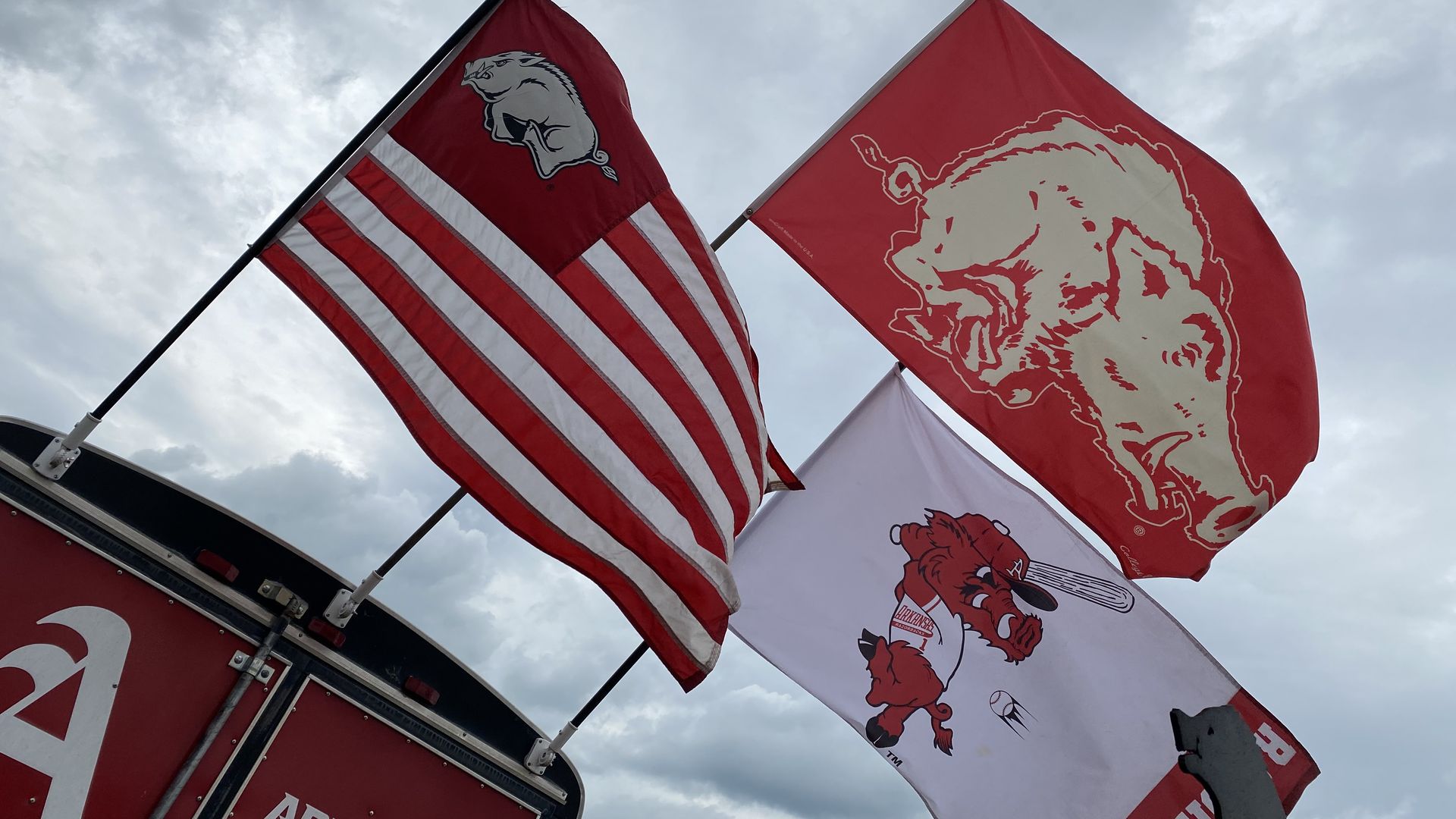 Three Razorback flags flop in the wind.