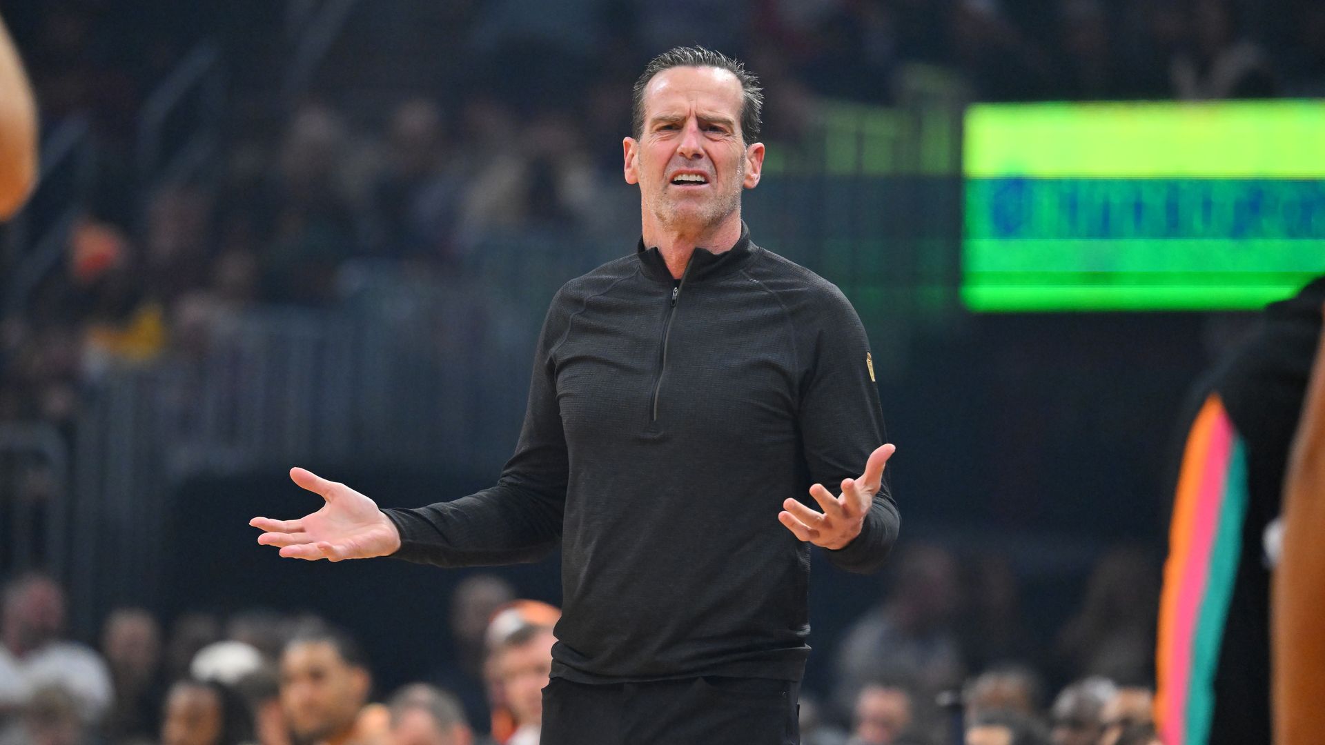 Man in black quarter zip on NBA court making a confused face 