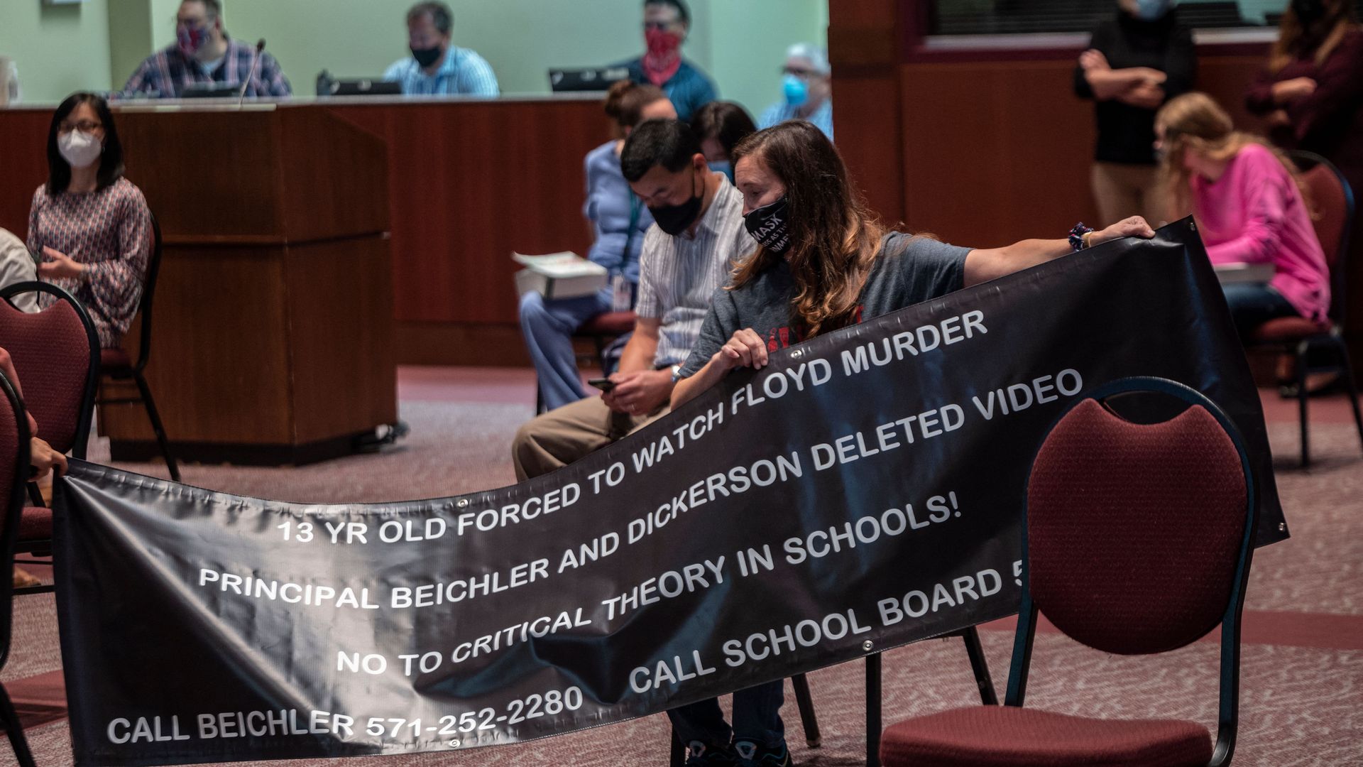 A woman holds up her sign against Critical Race Theory (CRT) being taught during a Loudoun County Public Schools board meeting 
