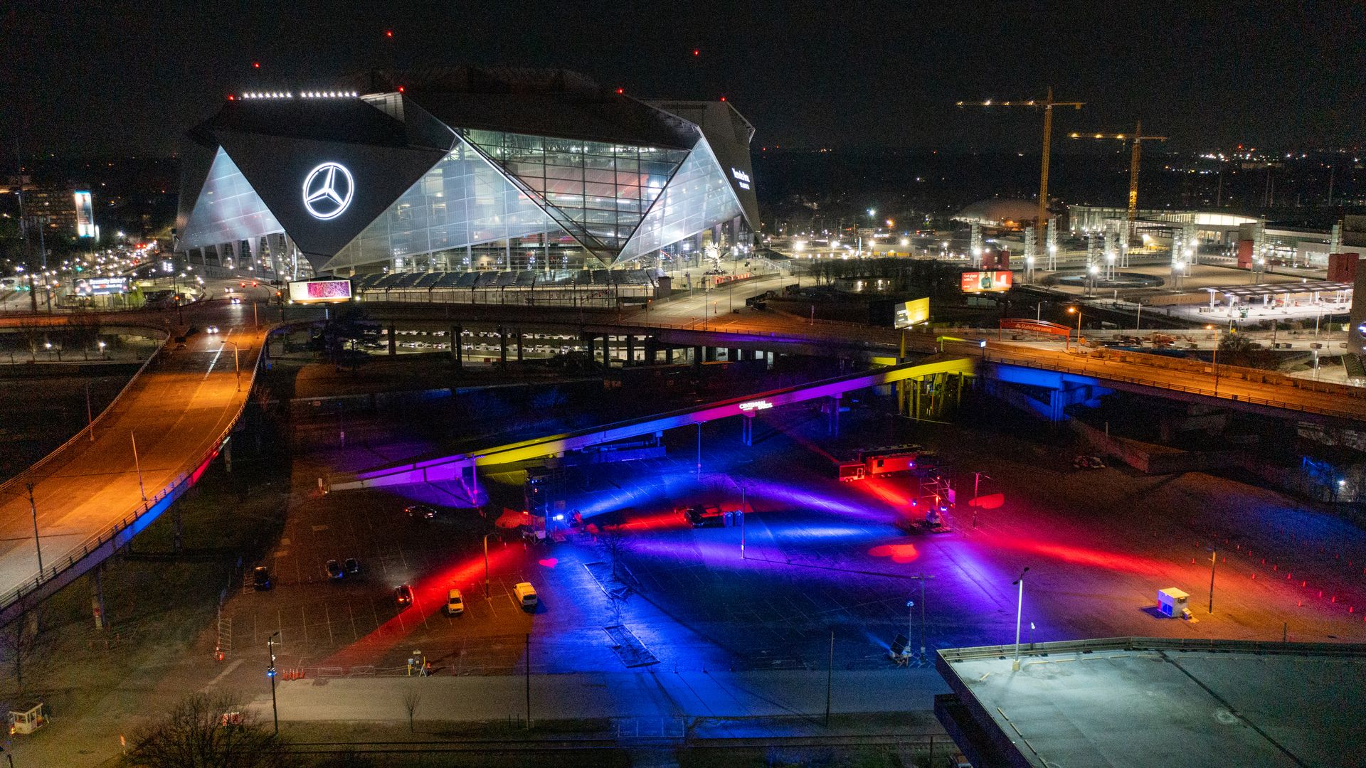 Colorful displays fill a huge parking light in front of a modern football stadium