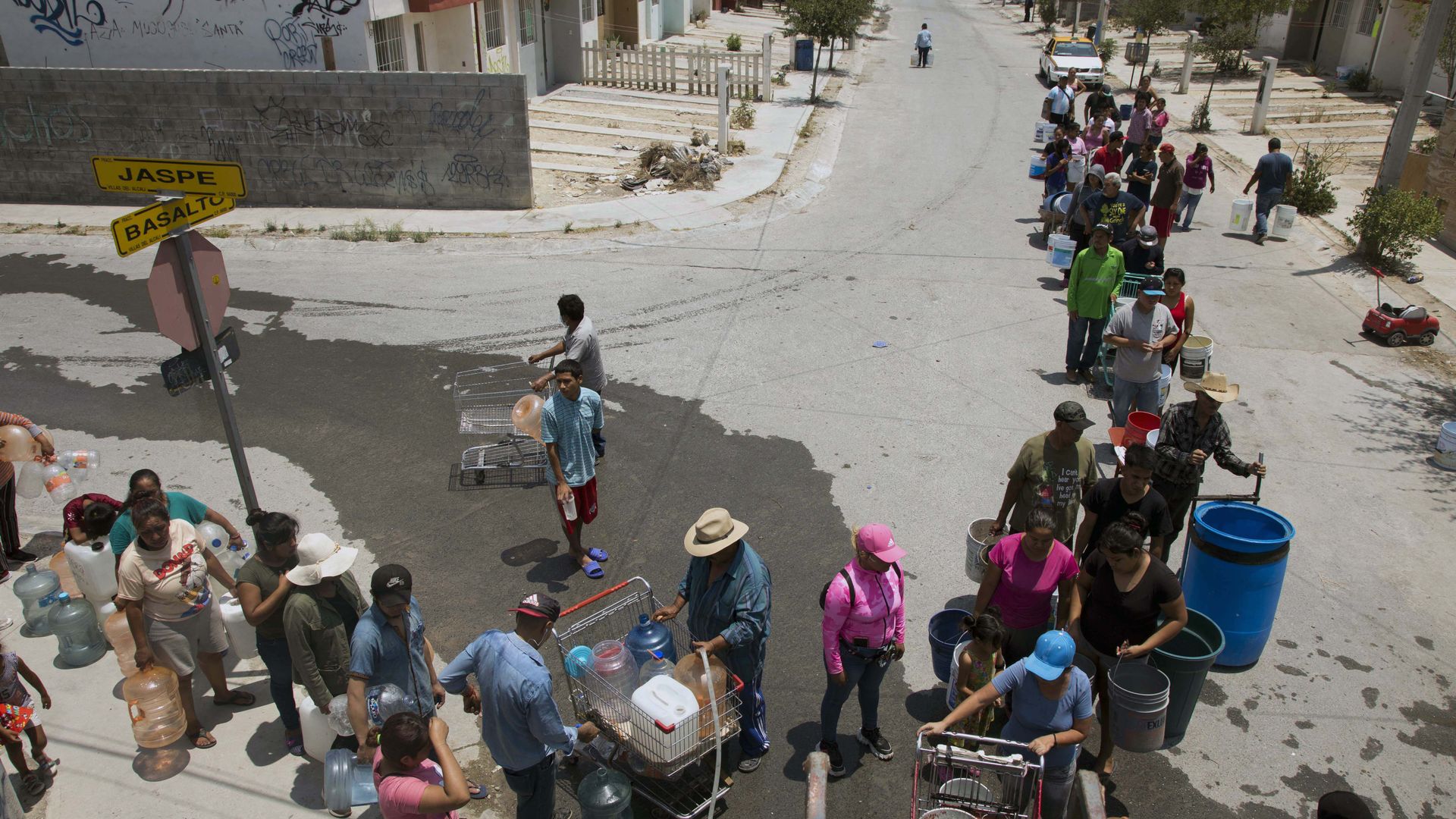 An overhead shot of people lined up on a street while holding buckets to collect clean water in Mexico 