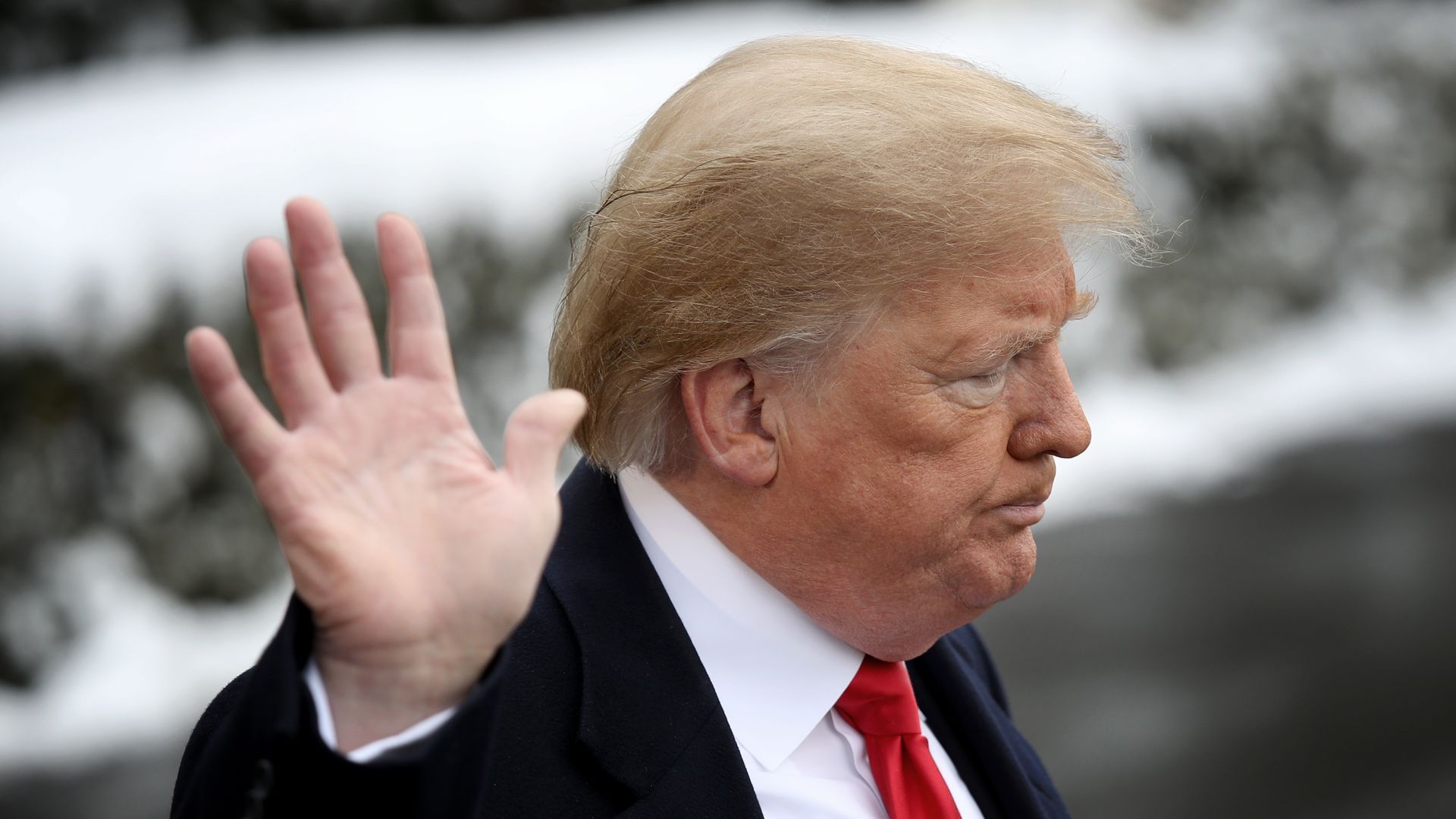 Donald Trump puts up hand to camera and looks away.