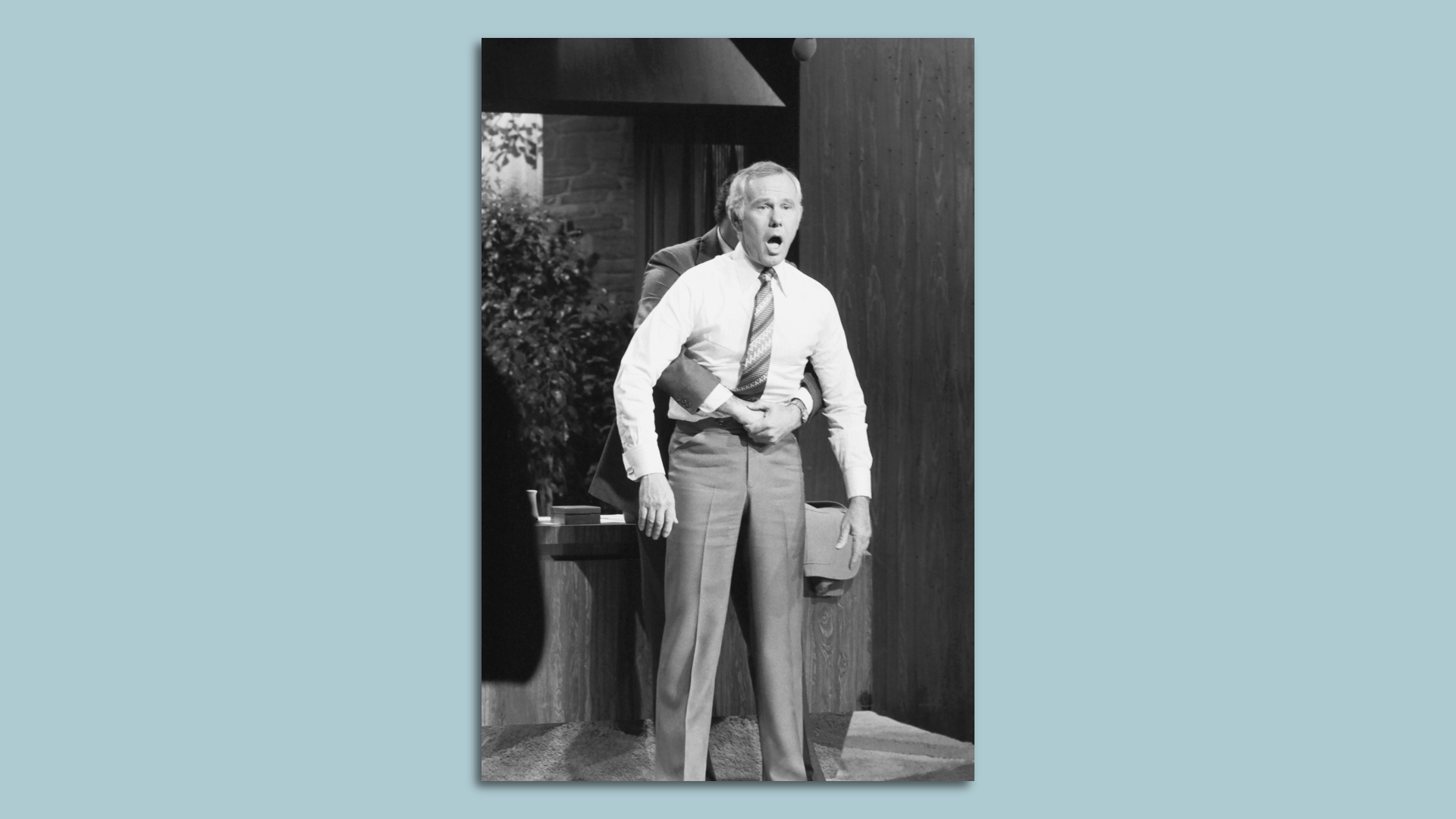 black and white photo of johnny carson getting the heimlich maneuver