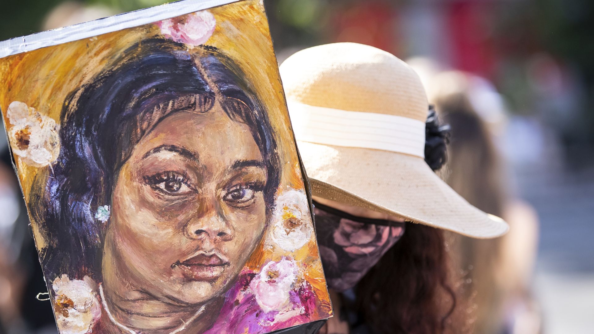 Artist Claudine Anrather wearing a mask holds her hand painted sign tribute to Breonna Taylor in Union Square Park, New York. 