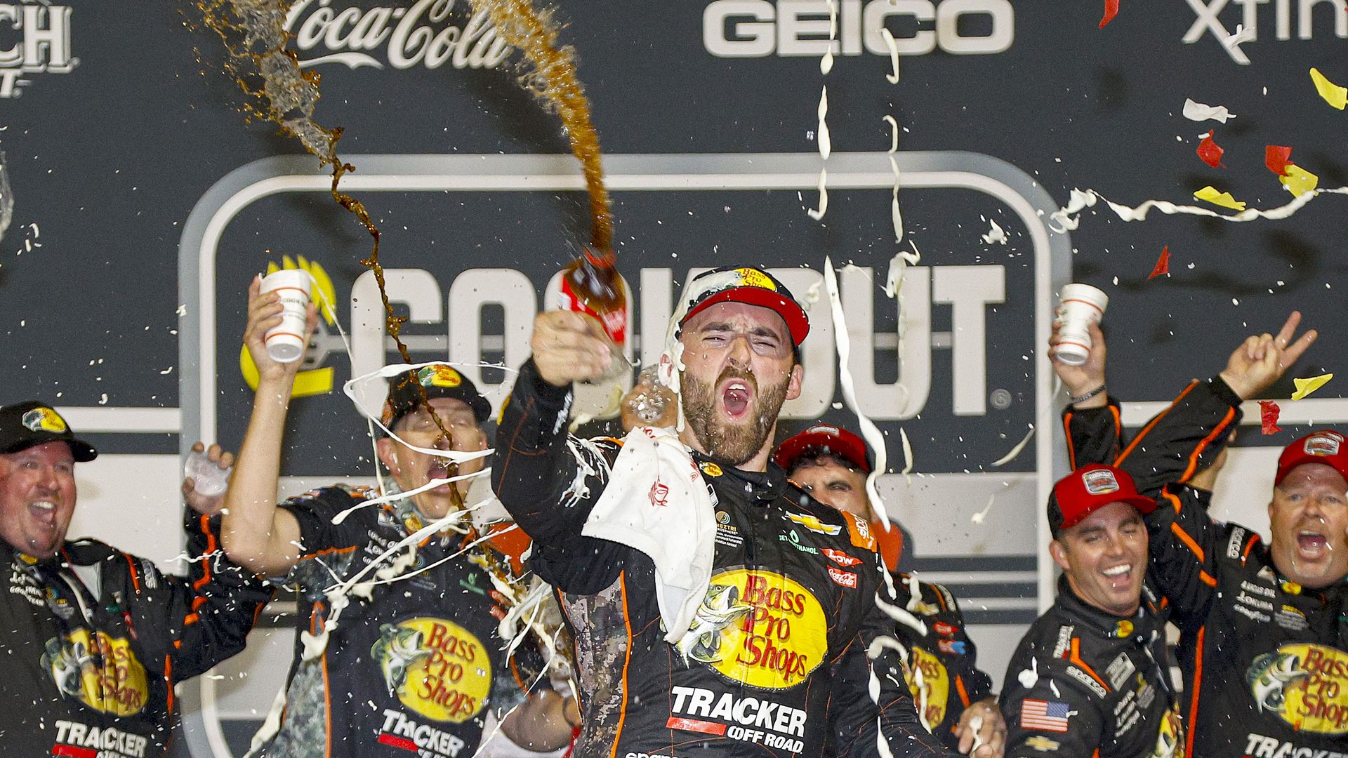A team wearing Bass Pro Shops gear cheering in the victory lane.