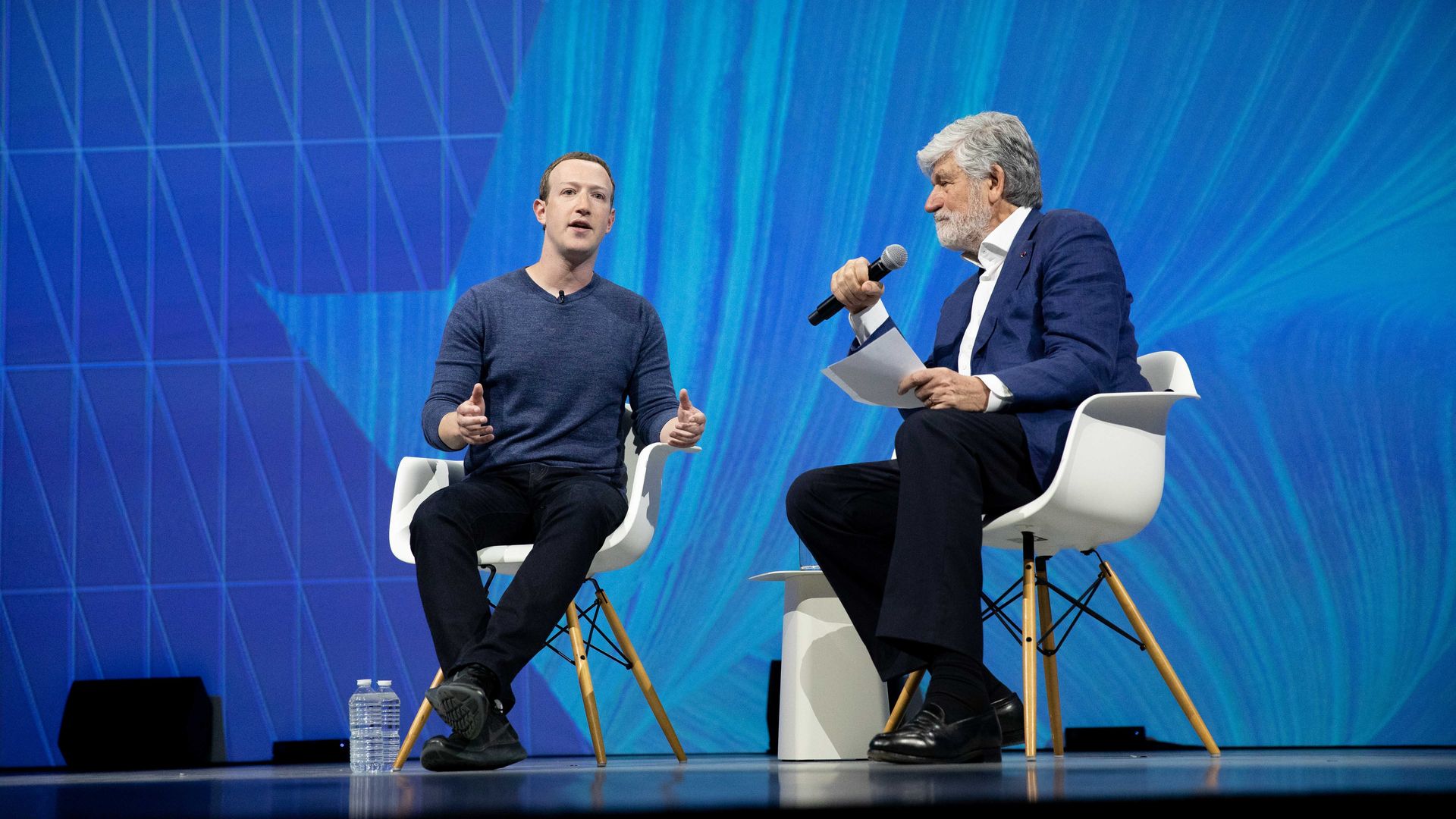 Mark Zuckerberg speaks to another man on stage at a conference