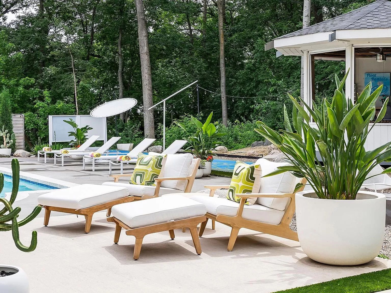 A patio with lounge chairs by a pool.